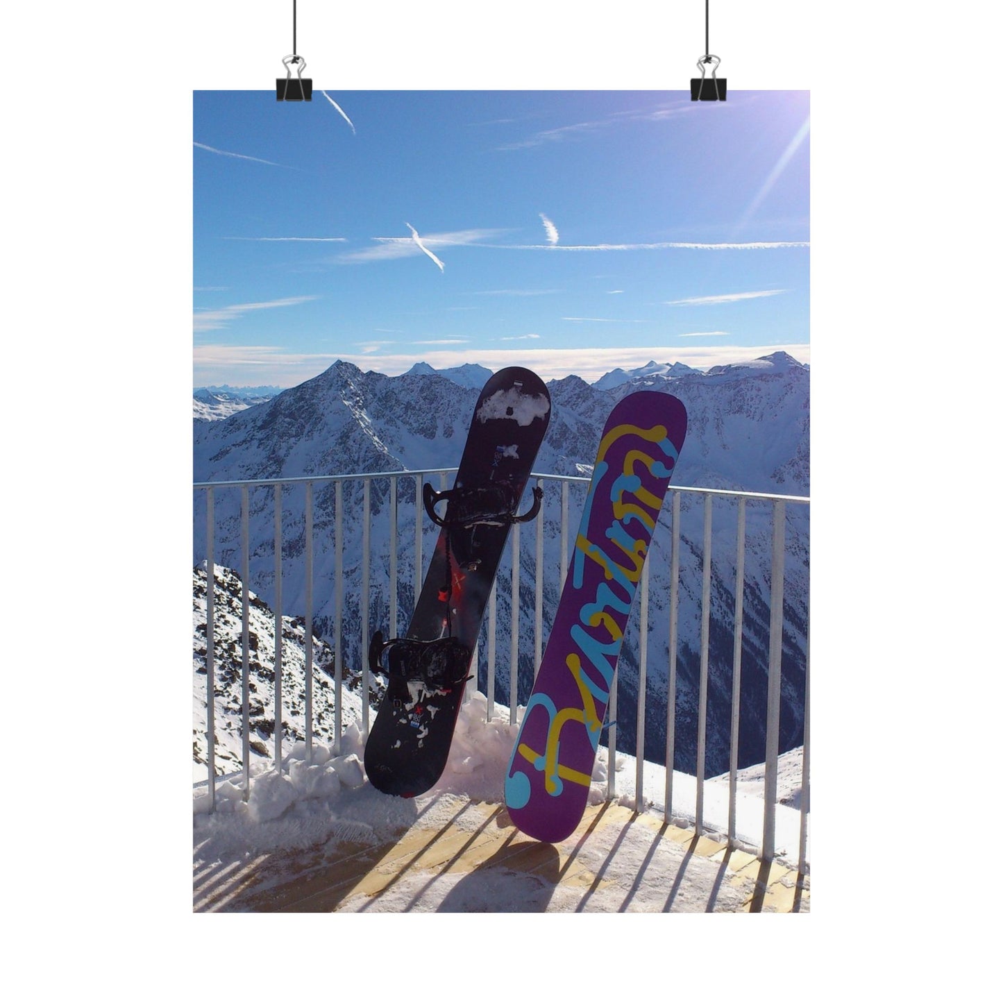 Two snowboards against a mountainous landscape with a clear blue sky.