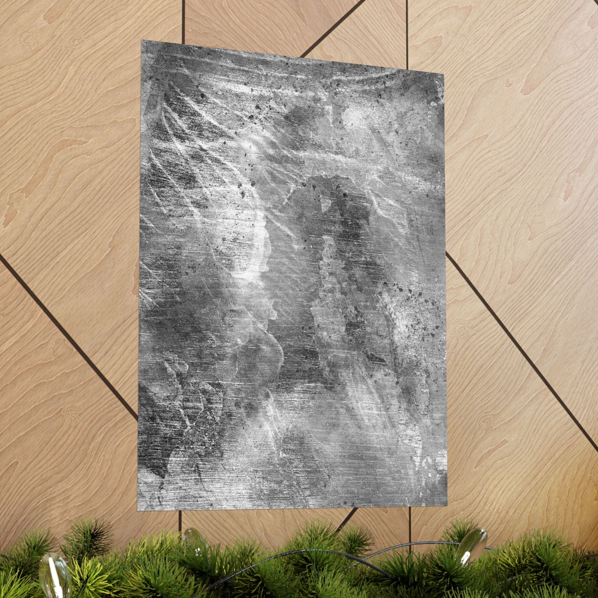 Abstract black and white textured paper on a wooden surface with greenery at the bottom.