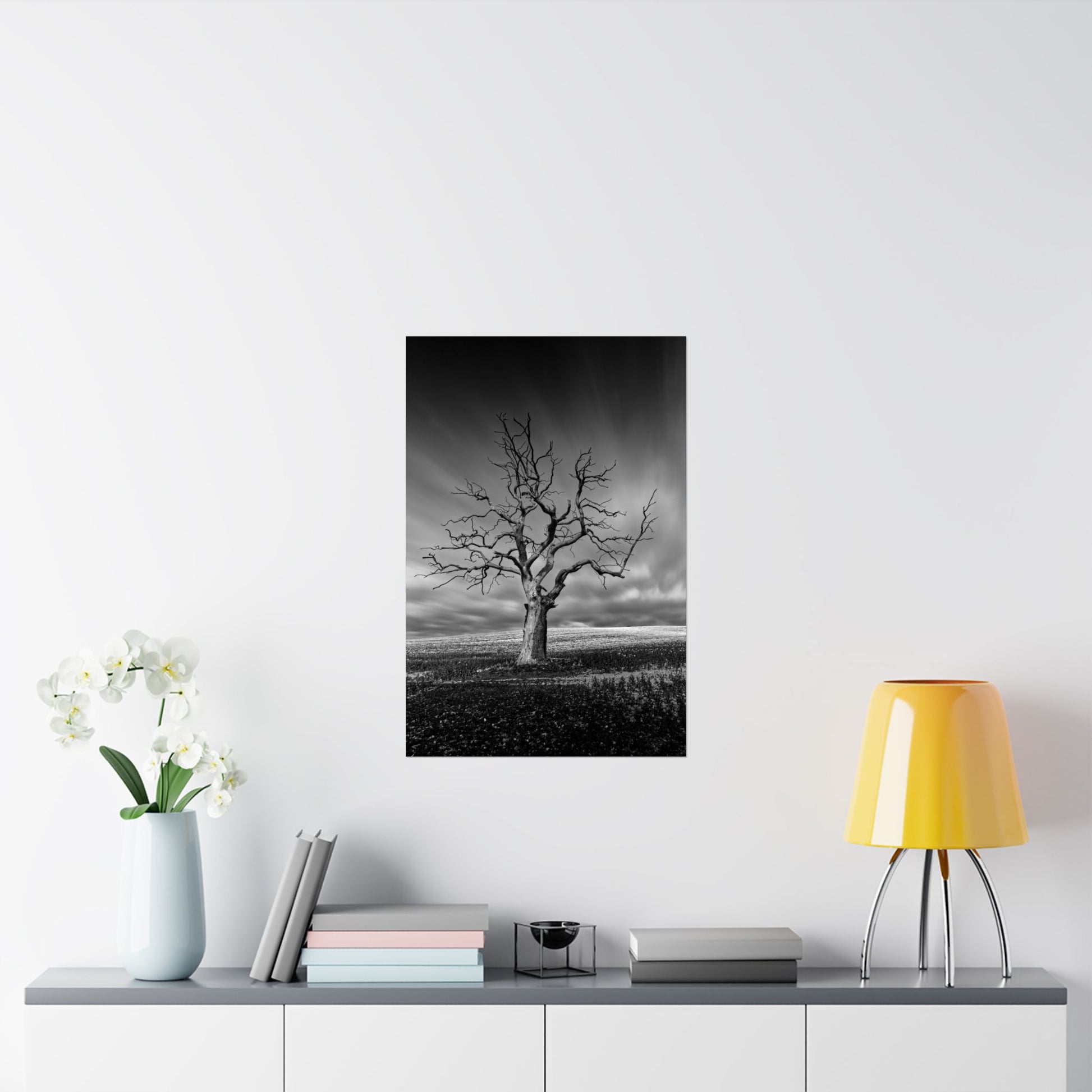 Framed black and white artwork of a tree on a wall above a shelf with decor items.