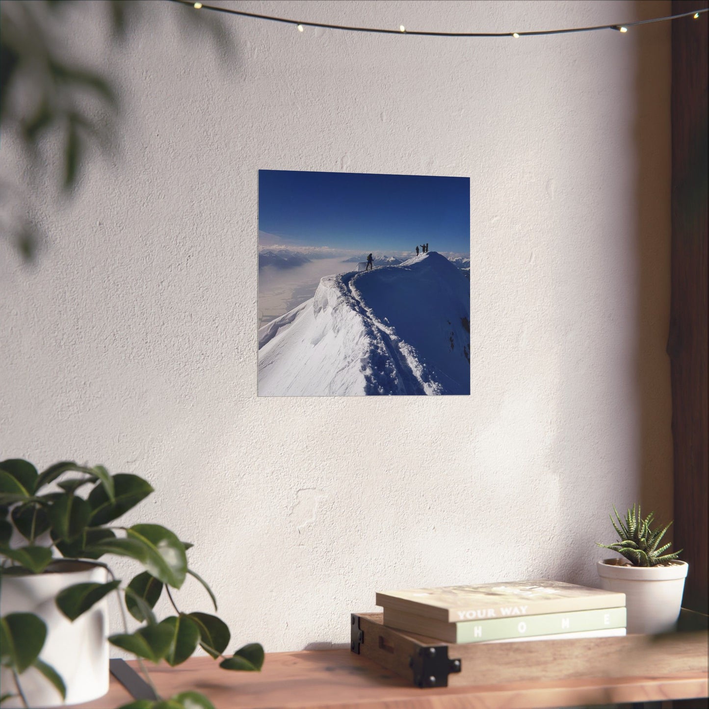 Poster of a snowy landscape with people on a mountain on a white wall above a wooden desk.