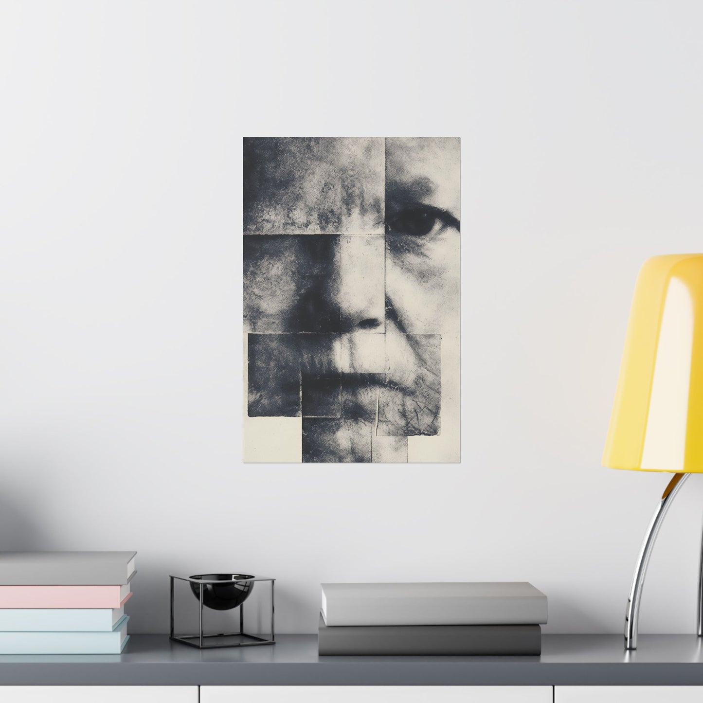 Abstract art piece on a wall above a shelf with books and a lamp.