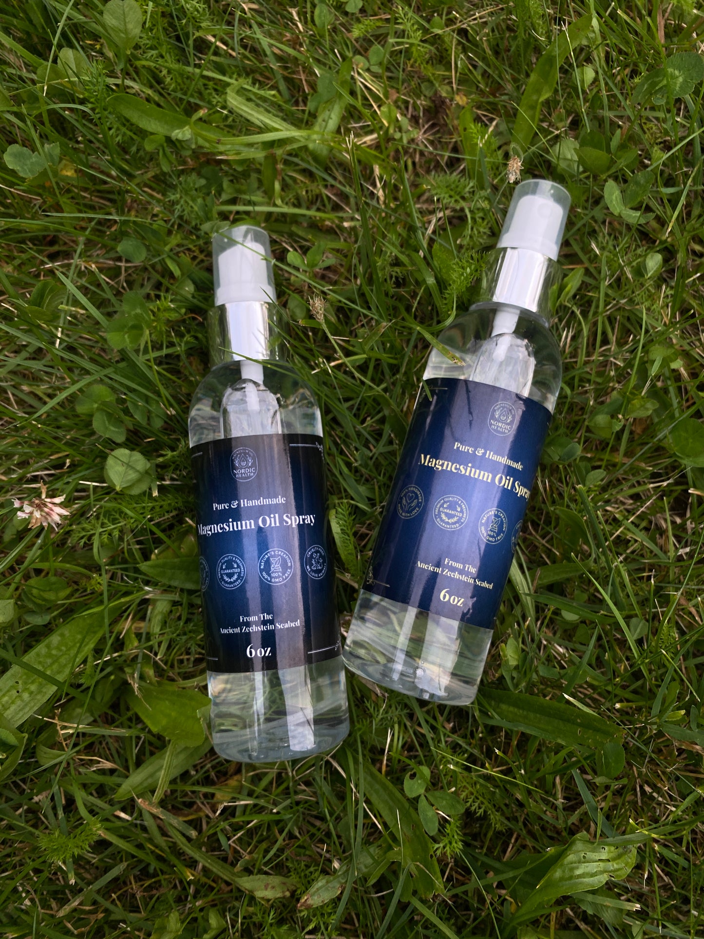 two bottles of magnesium oil spray laying in grass