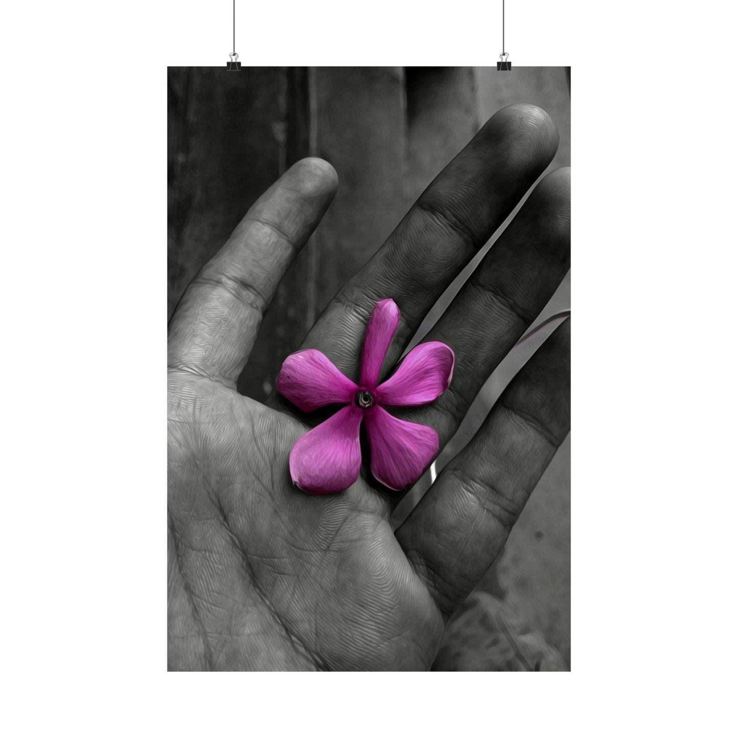 Purple flower held delicately between fingers against a black and white background