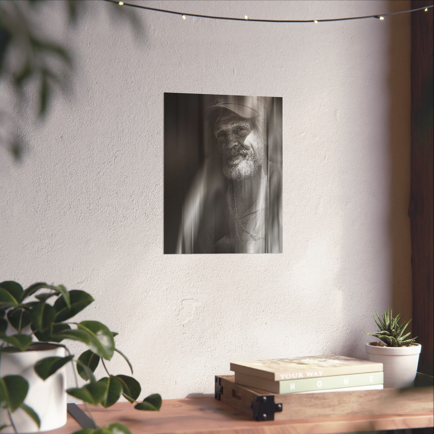 Framed black and white portrait of a man on a wall above a wooden desk with plants.