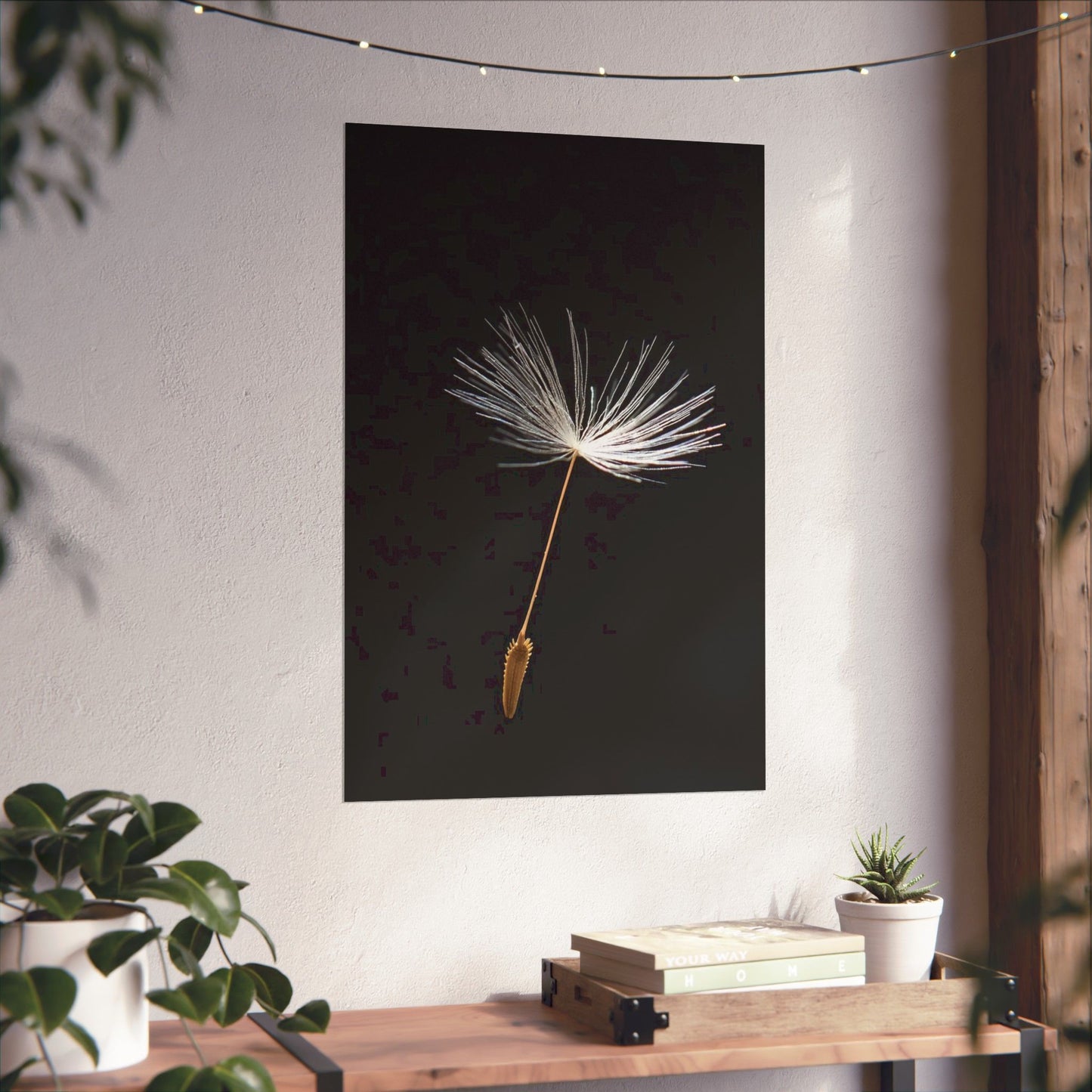 Poster of a dandelion seed head on a wall with a wooden table and plants below.