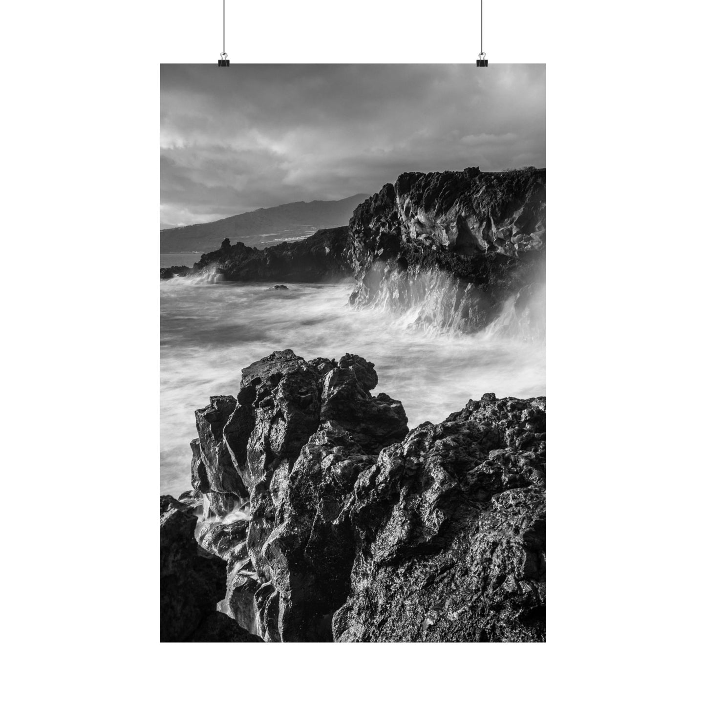 Black and white photograph of rocky coastline with waves crashing against the shore.