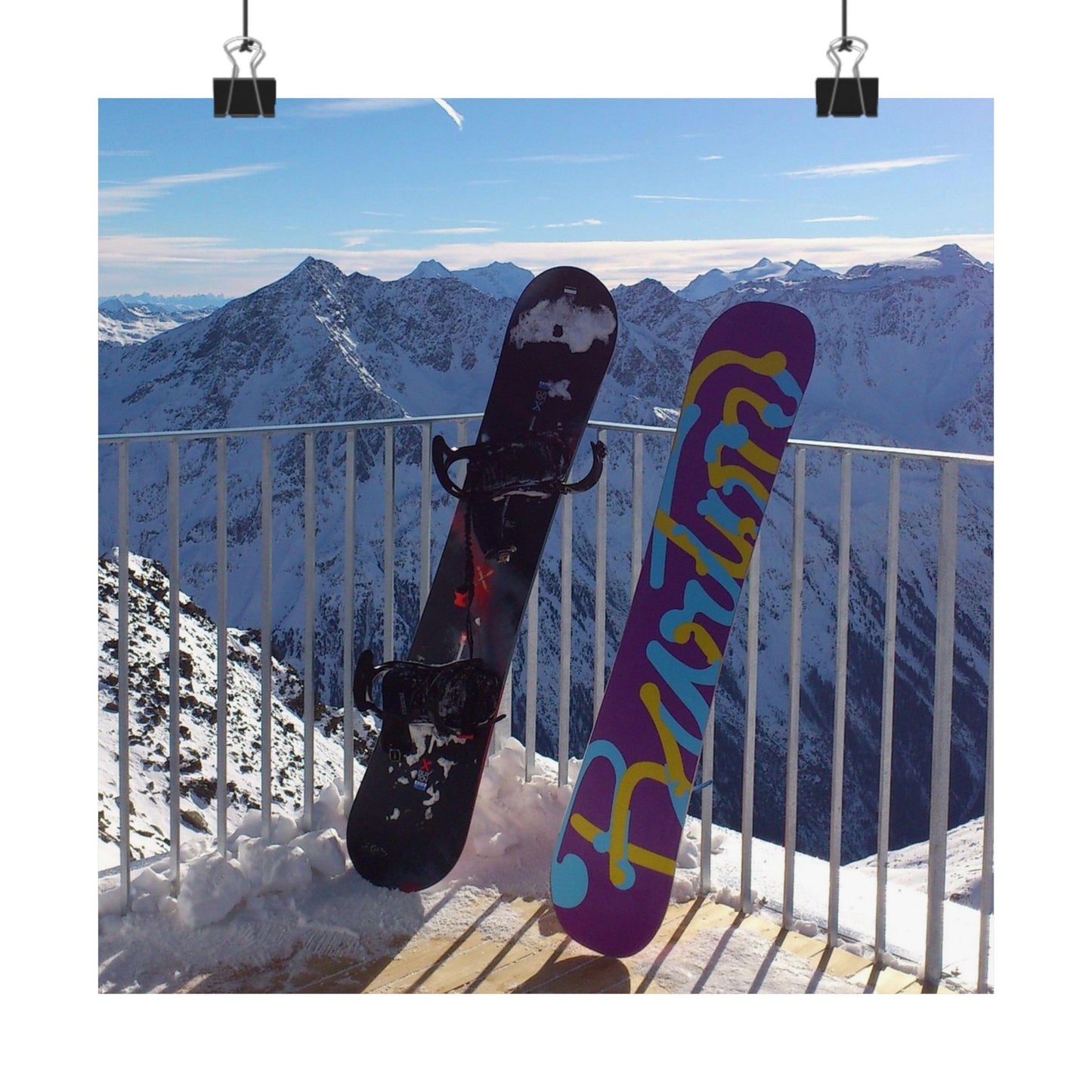 Two snowboards leaning against a railing with a mountainous landscape in the background