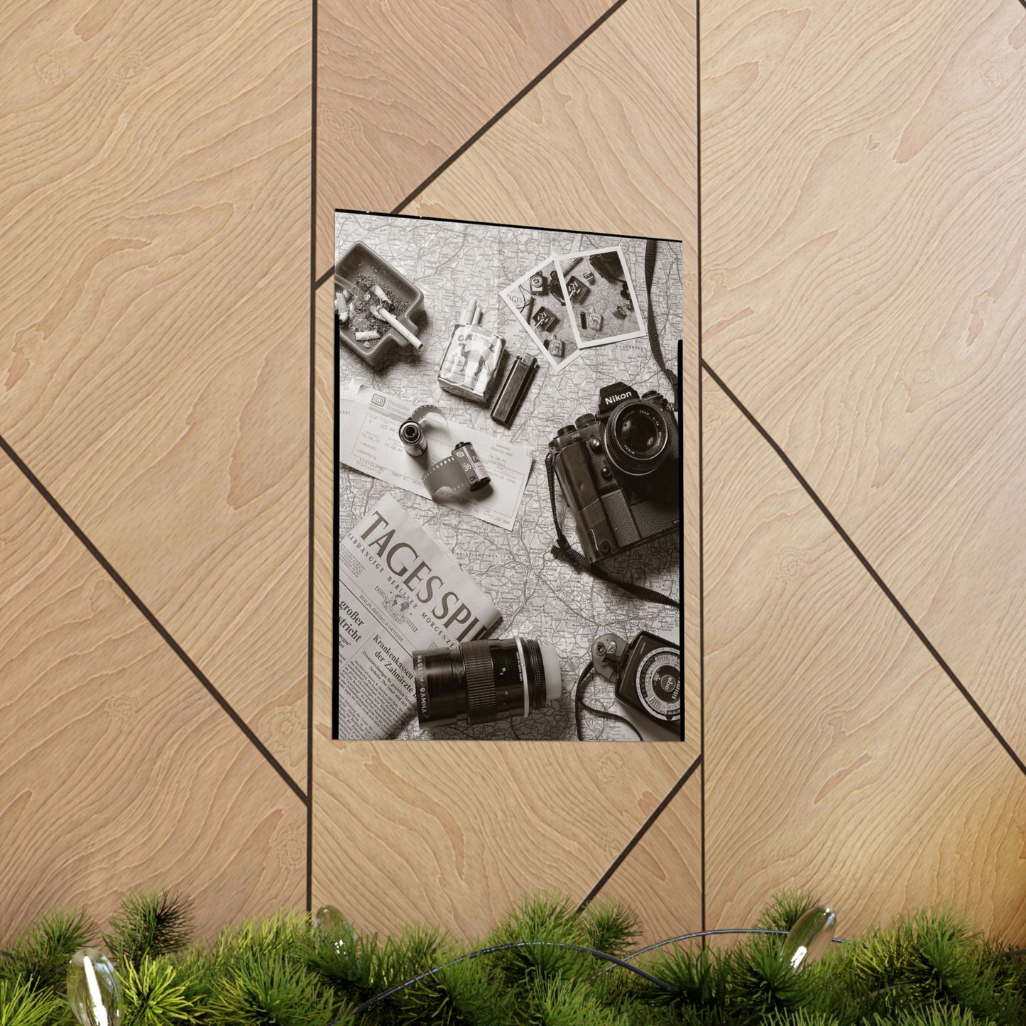Framed photo of vintage camera and film on a newspaper with decorative elements on a wooden surface.