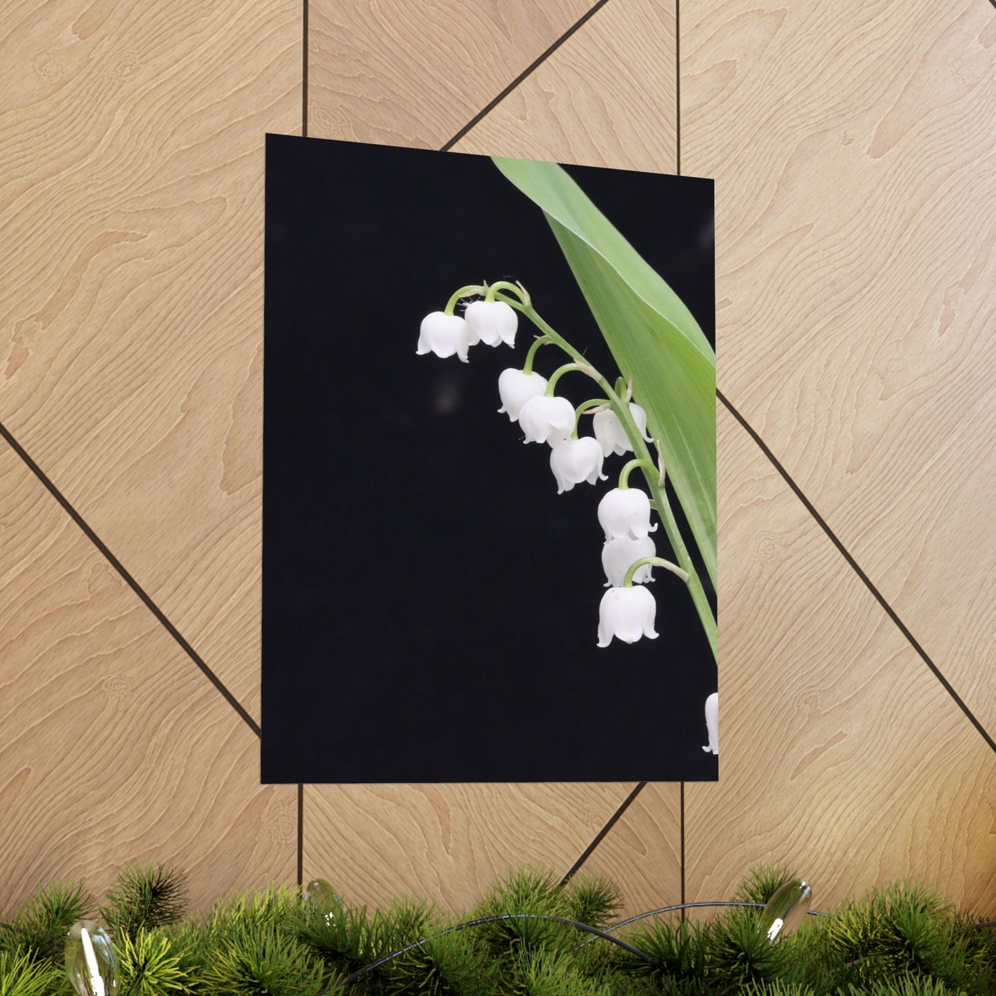 Poster of white flowers on a black background, leaning against a wooden wall.