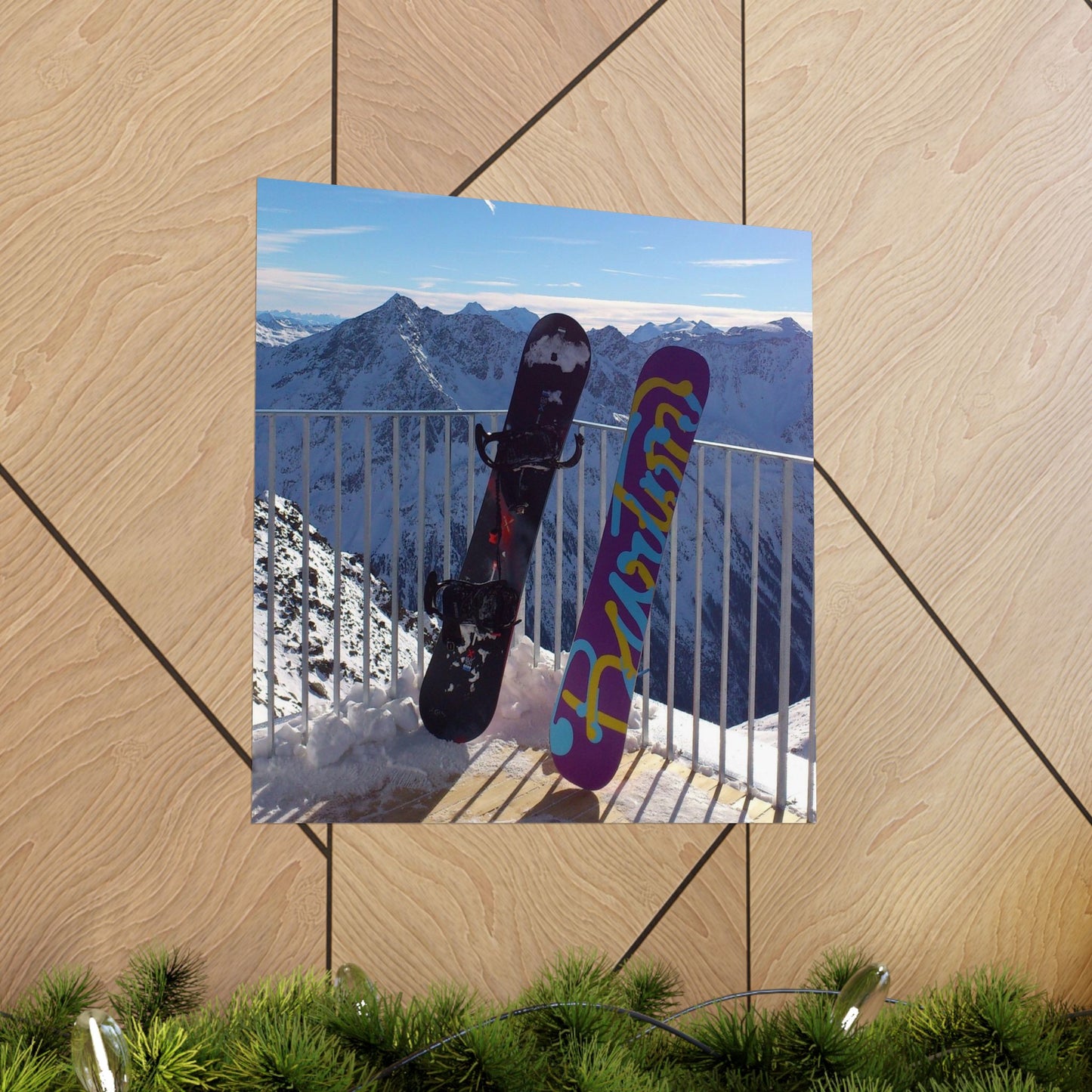 Two snowboards against a mountain backdrop on a wooden surface.