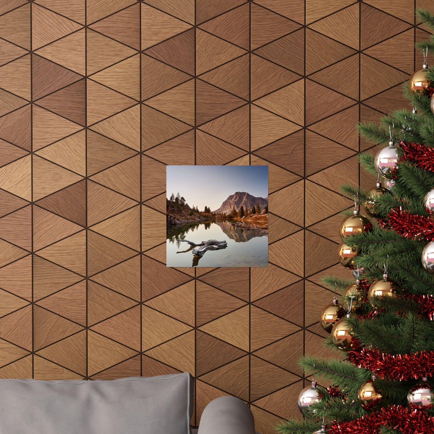 Wooden wall with geometric pattern, framed picture of a mountain landscape, and a decorated Christmas tree.