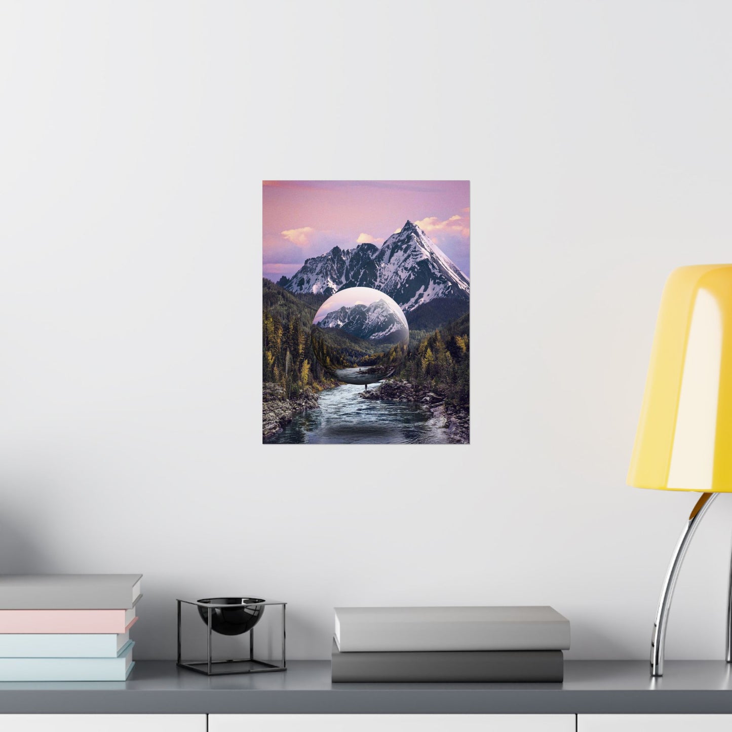 Framed artwork of a mountain landscape with a river on a white wall above a shelf.