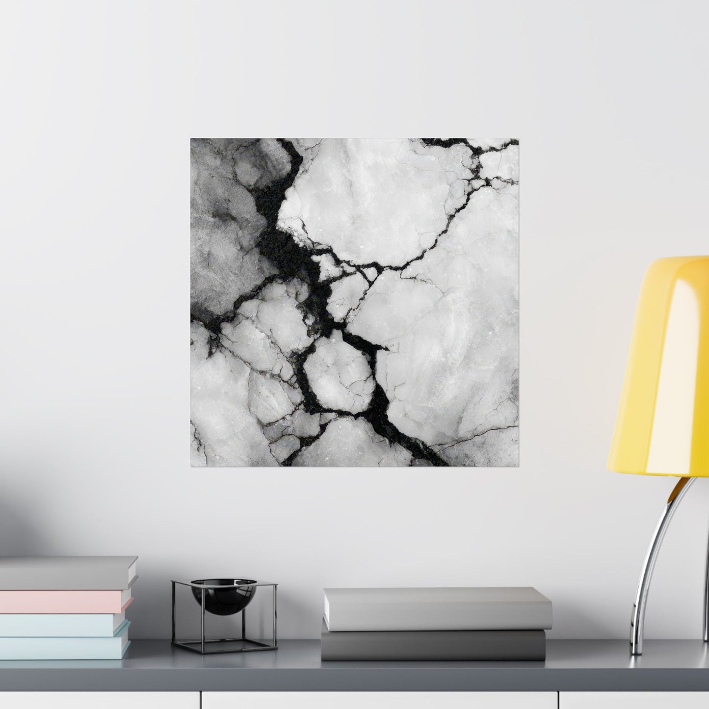 Marble-patterned wall art on a white wall with books and a lamp in the foreground.