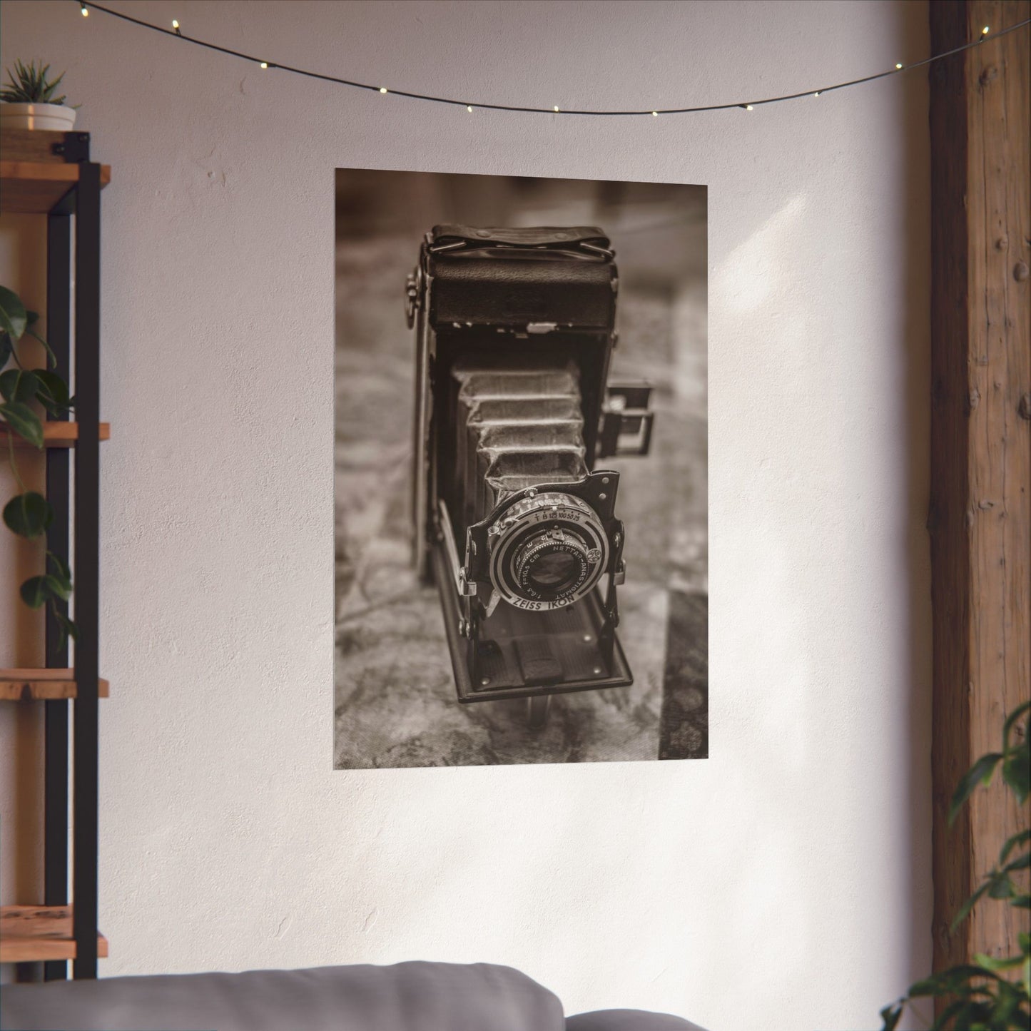 Vintage camera poster on a wall with string lights and a plant.