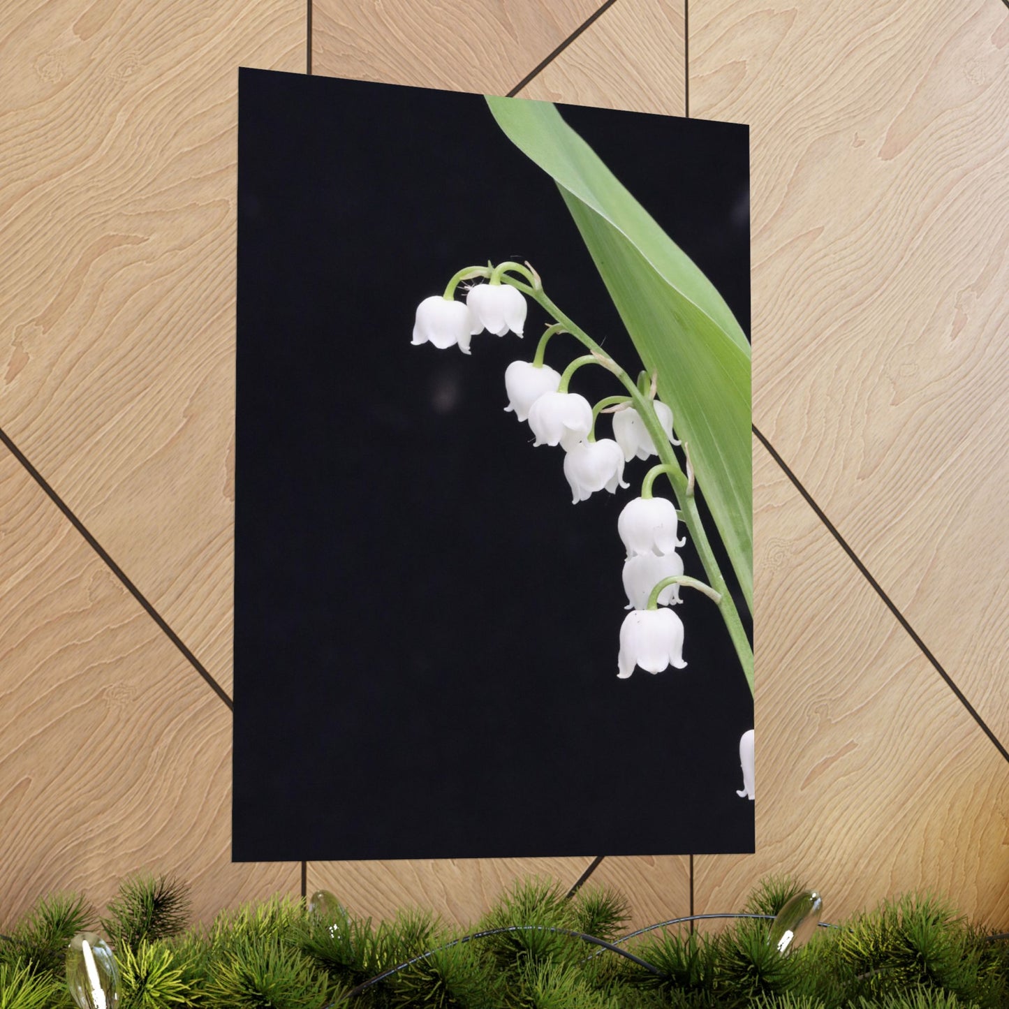 Poster of white flowers on a black background, leaning against a wooden wall.