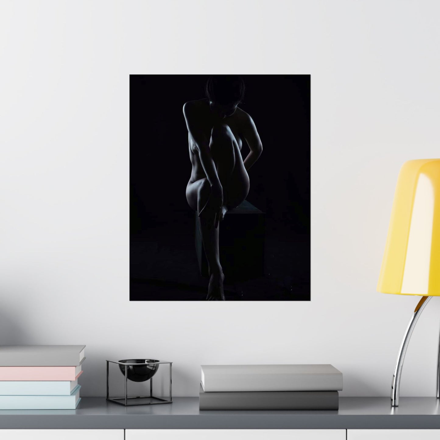 Silhouette of a nude person against a black background on a wall above a shelf.