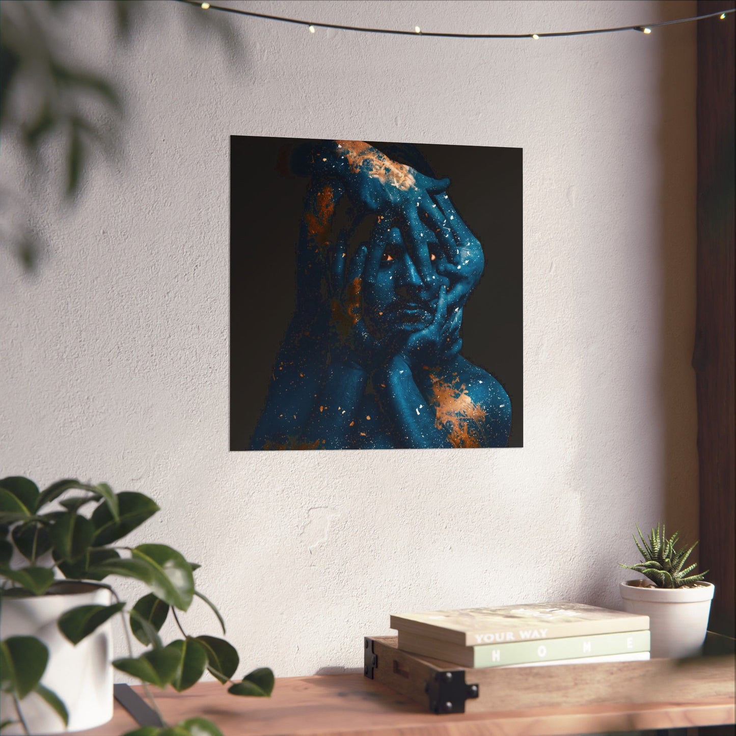 Abstract art piece on a wall above a wooden table with plants and books.