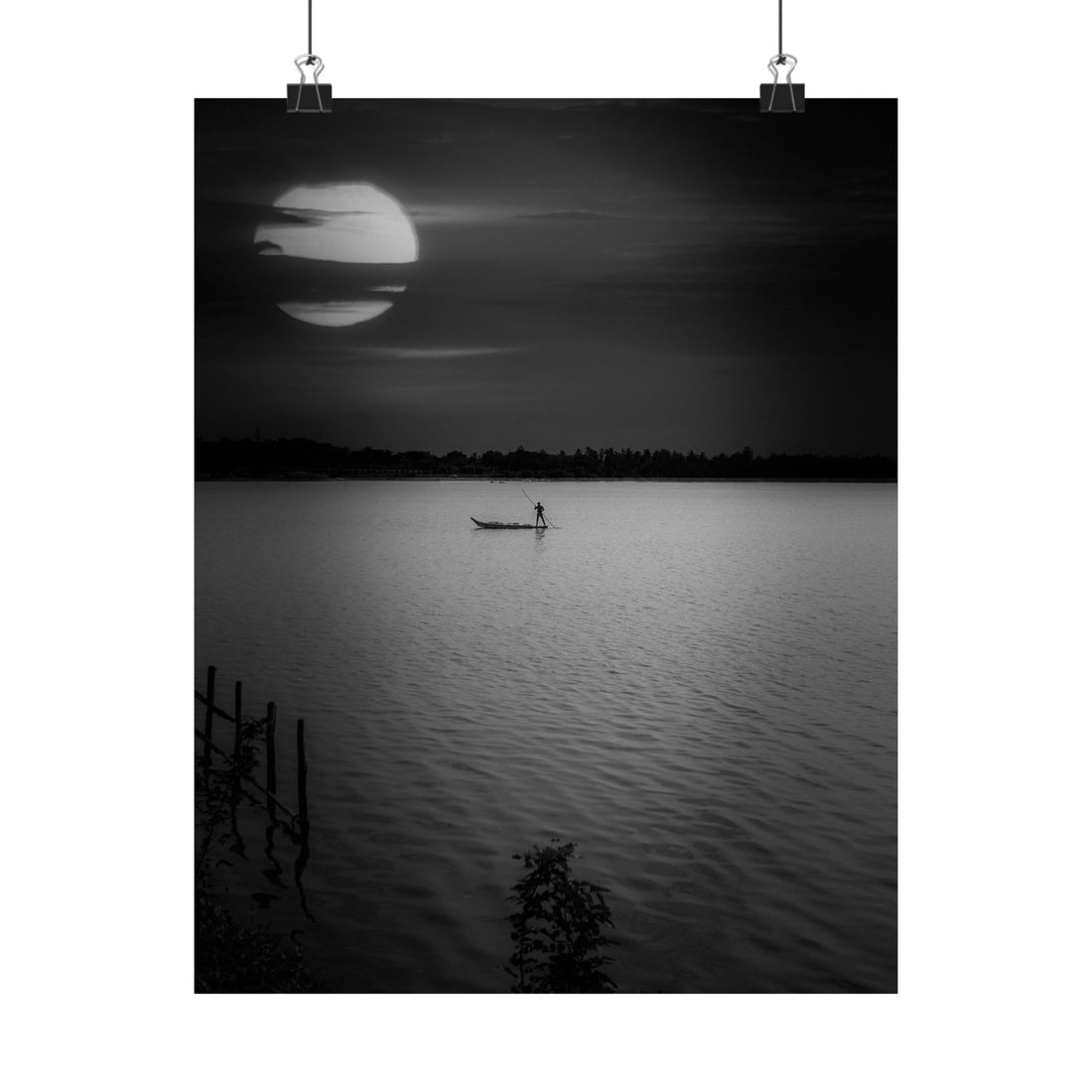Silhouette of a person in a boat on a calm lake at sunset or sunrise.