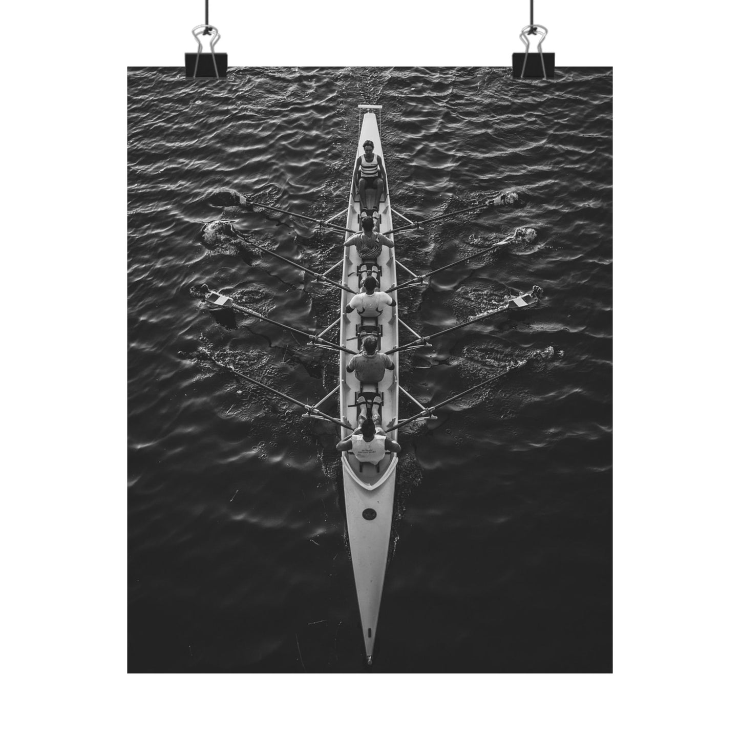 Black and white photo of a rowing boat with rowers on water