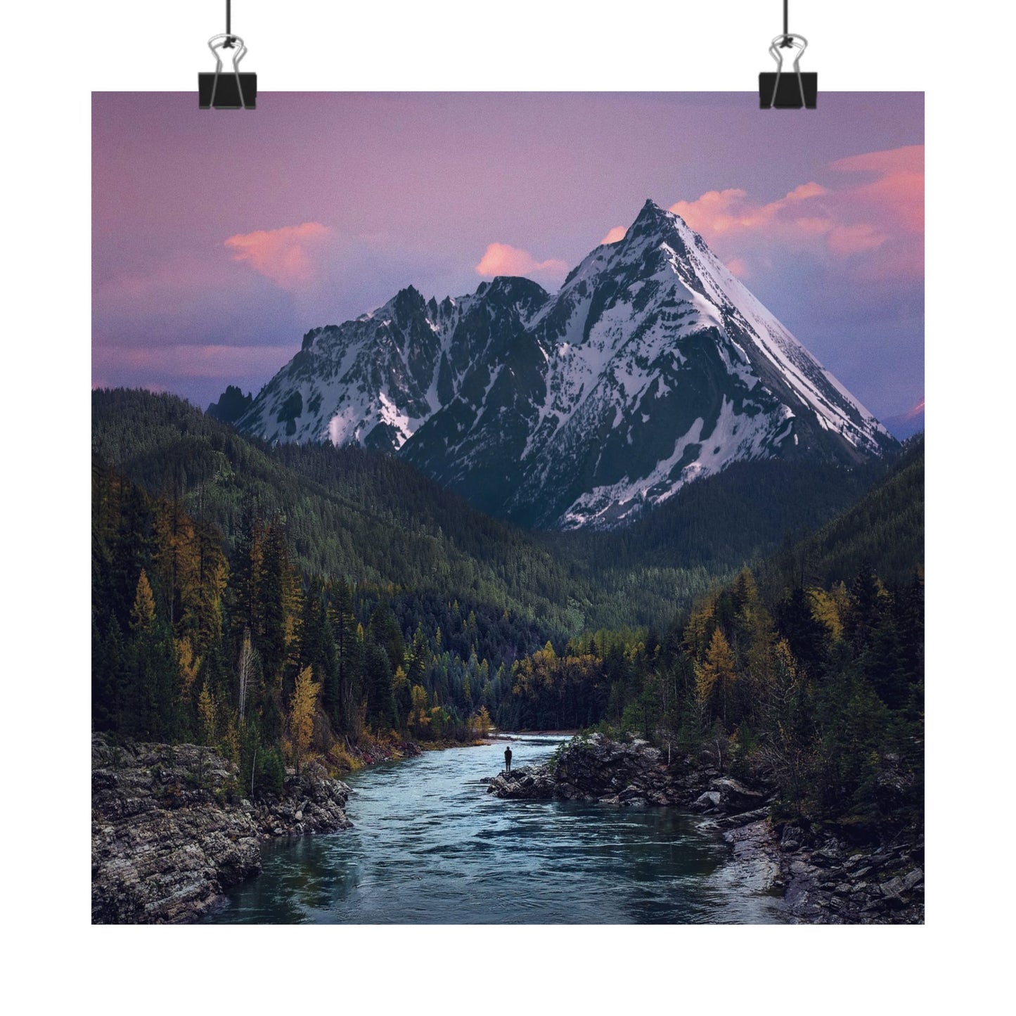 Mountain landscape with a river and a person standing on a rock at sunset.