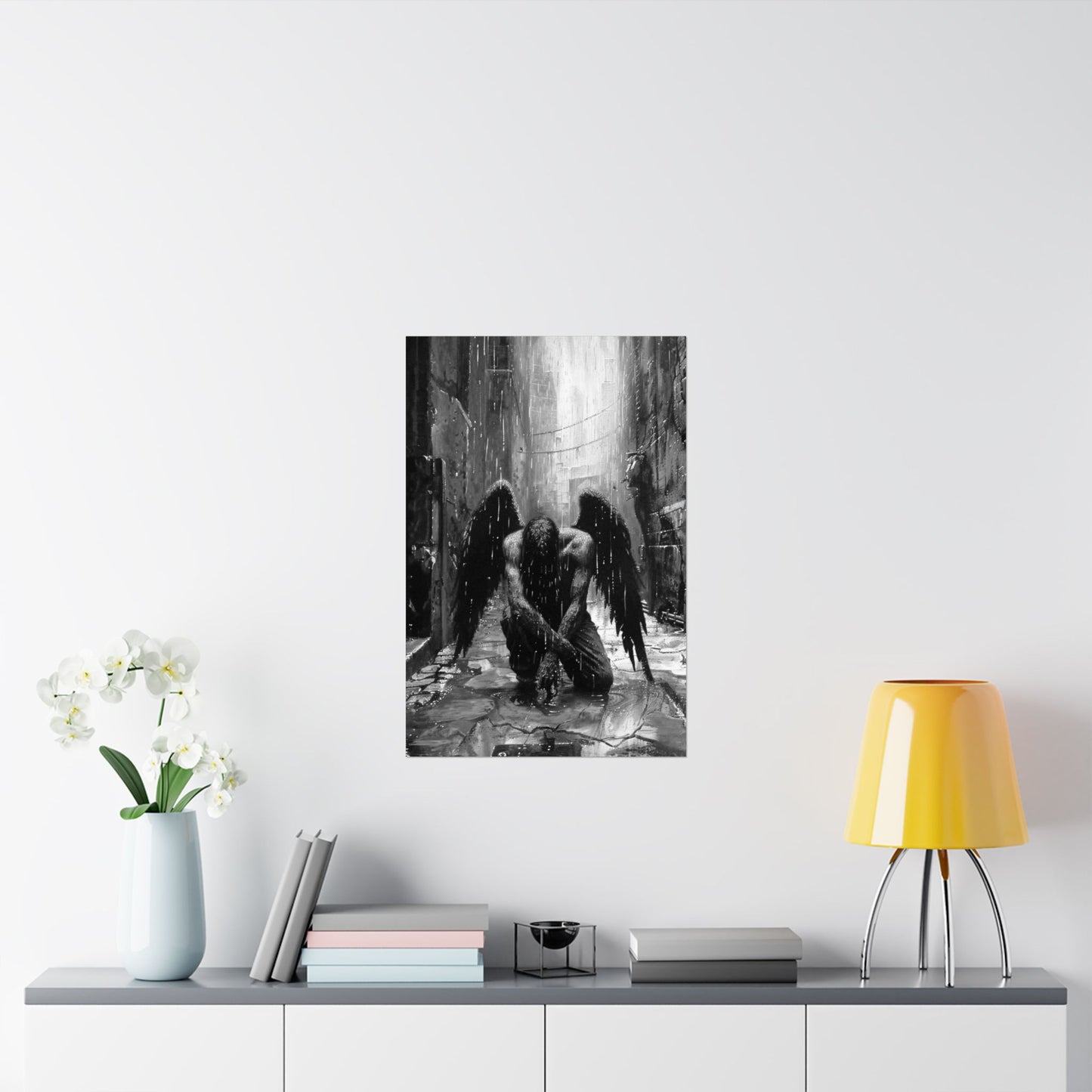Framed artwork of a black and white angelic figure on a wall above a table with decor items.