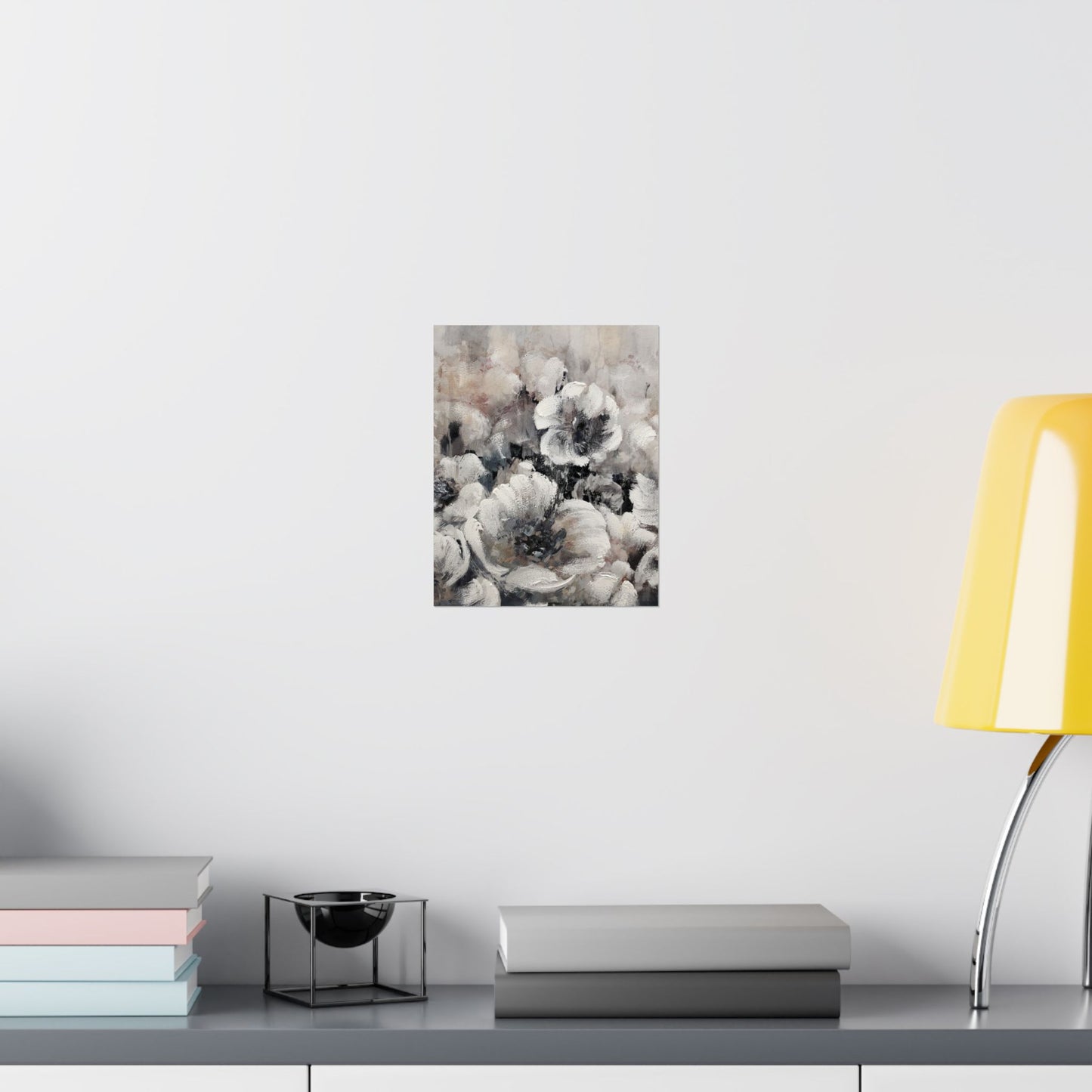 Floral art print on a wall above a desk with books and a lamp.