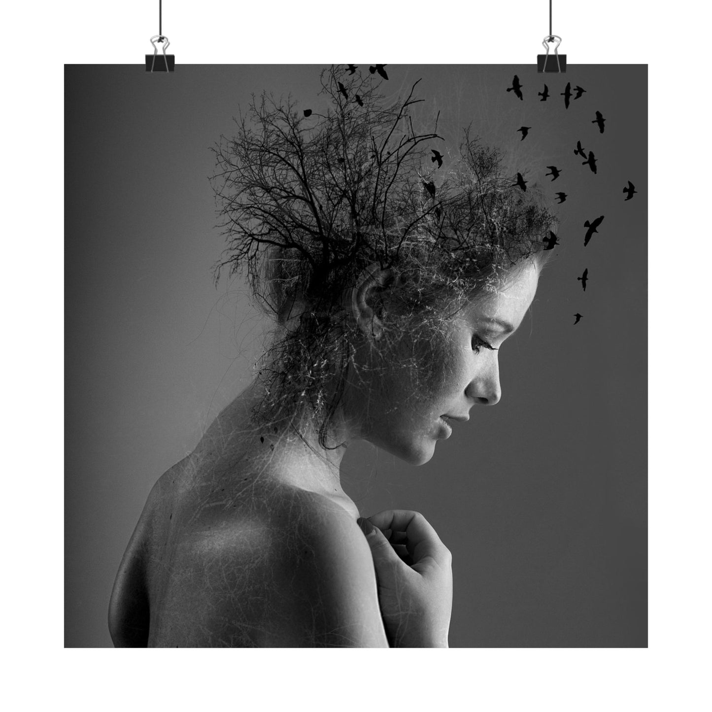 Black and white artistic photo of a woman with tree branches and birds superimposed on her hair.
