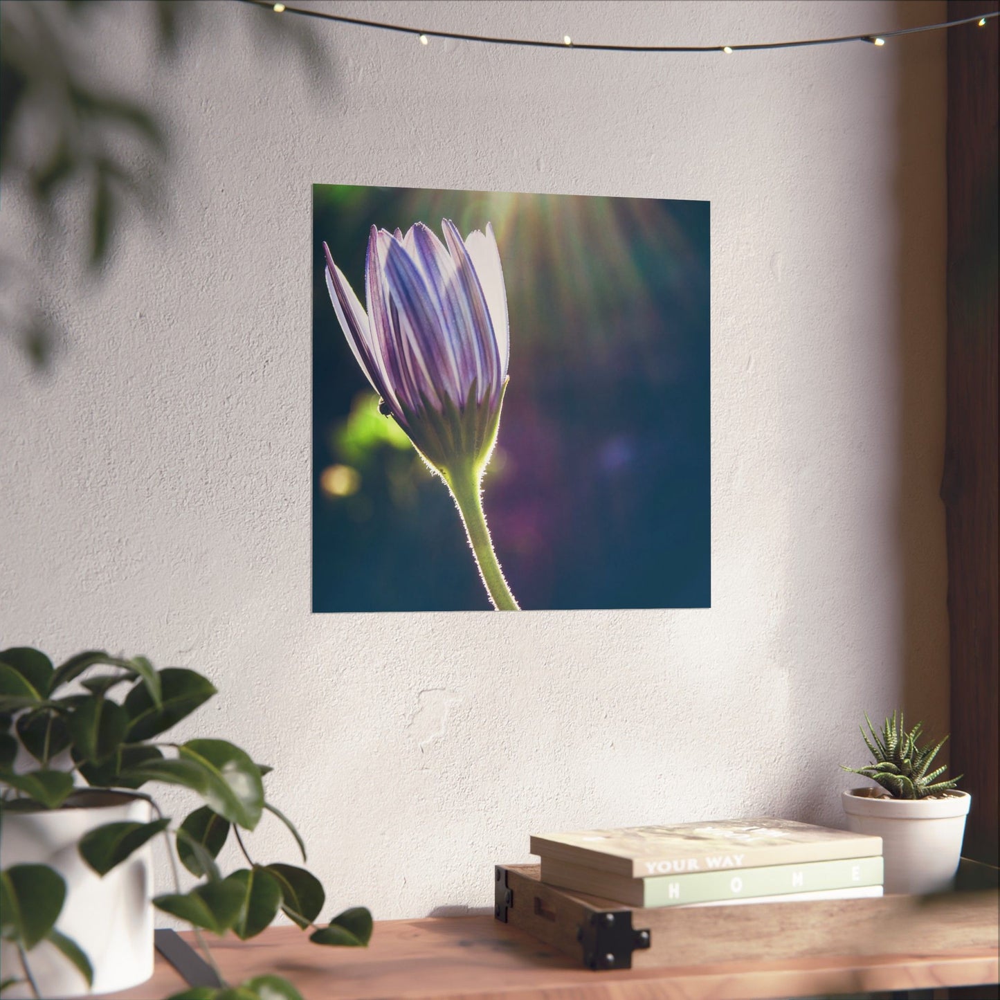Flower painting on a wall above a wooden desk with plants