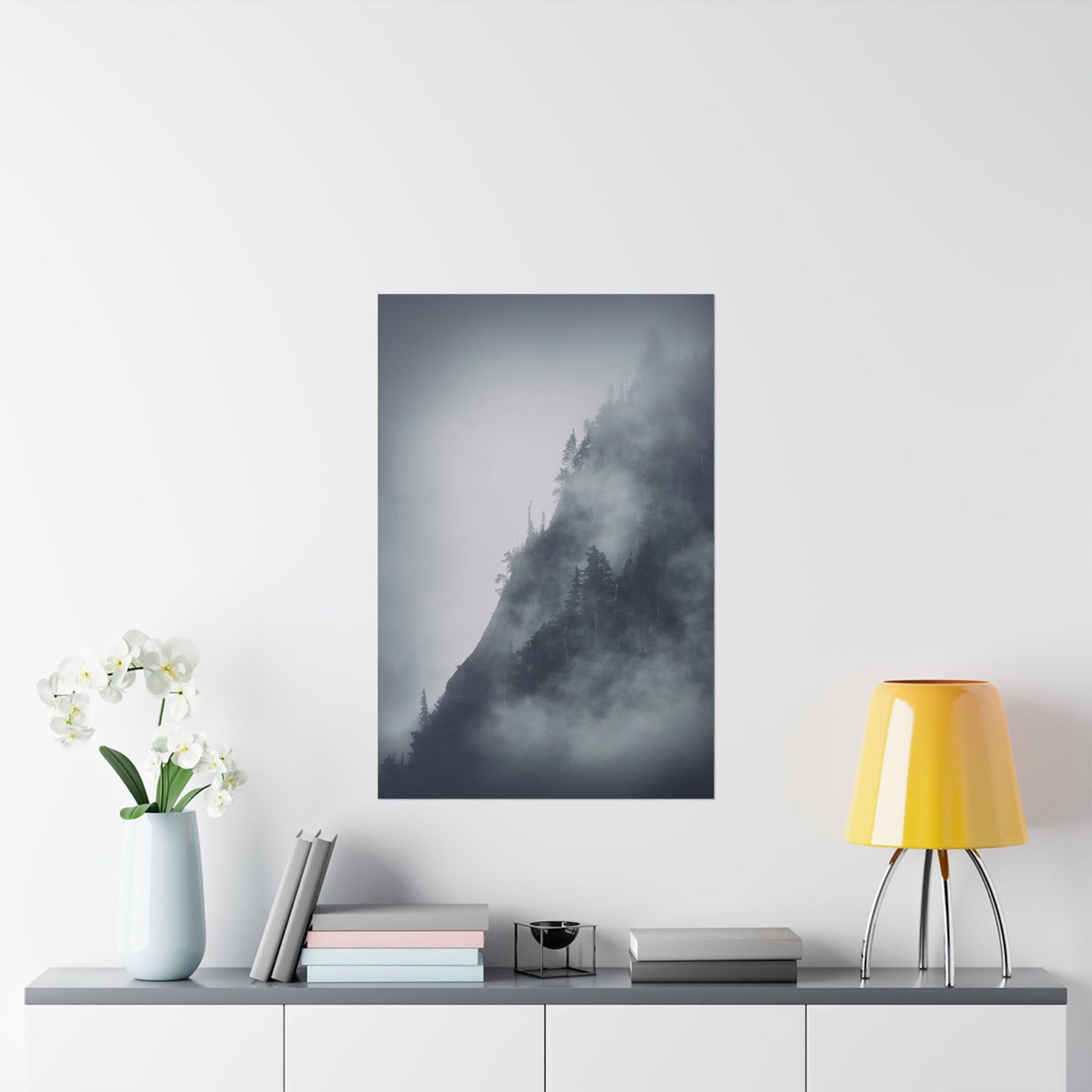 Framed artwork of a misty landscape on a wall above a table with decor items.