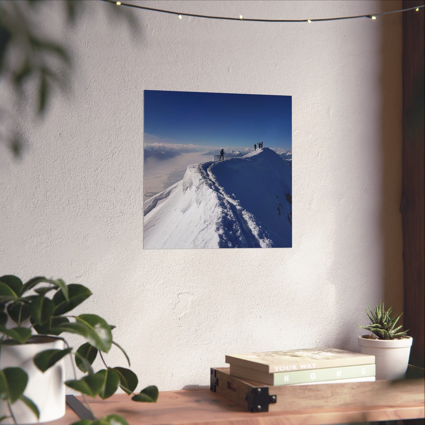 Poster of a snowy mountain landscape on a wall above a desk with plants and books.