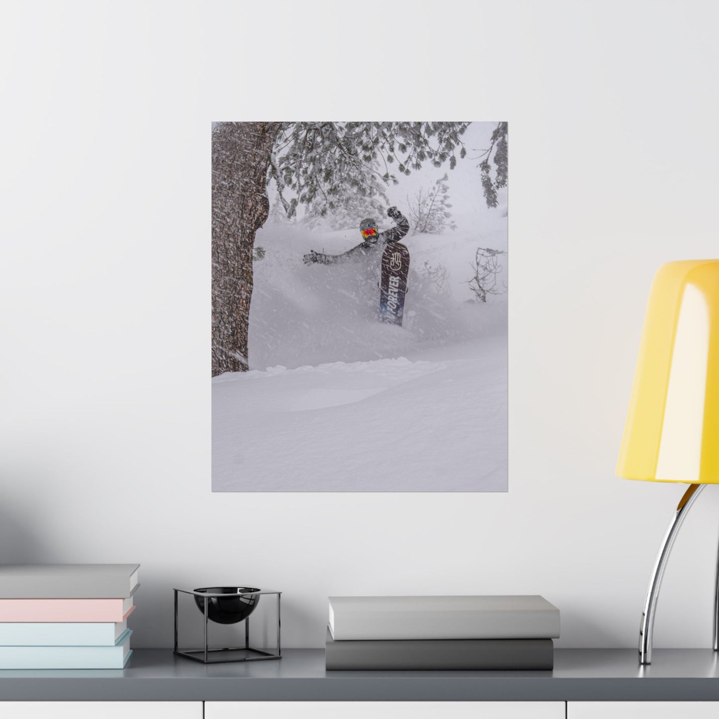 Poster of a person snowshoeing in a snowy landscape on a wall above a desk with books and a lamp.