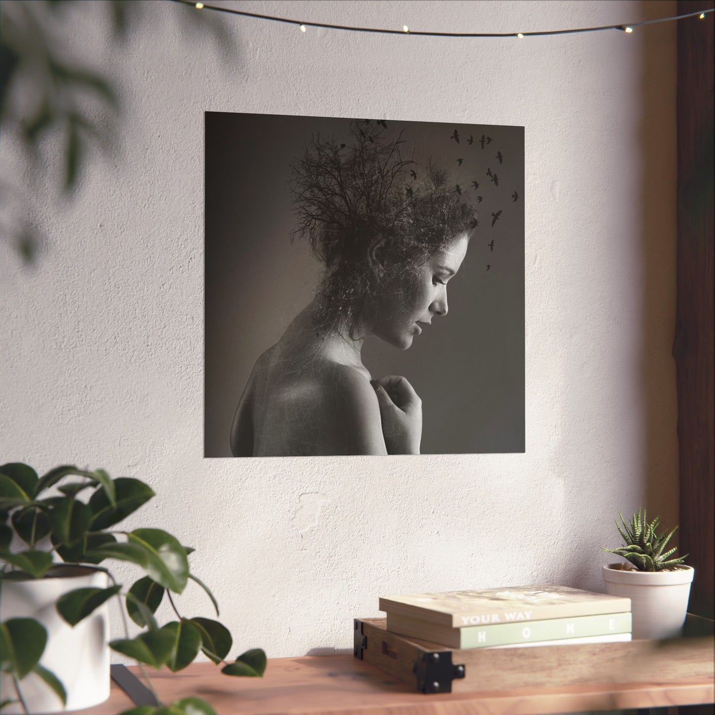Artistic portrait of a woman with birds on her head displayed on a wall above a wooden table with plants.