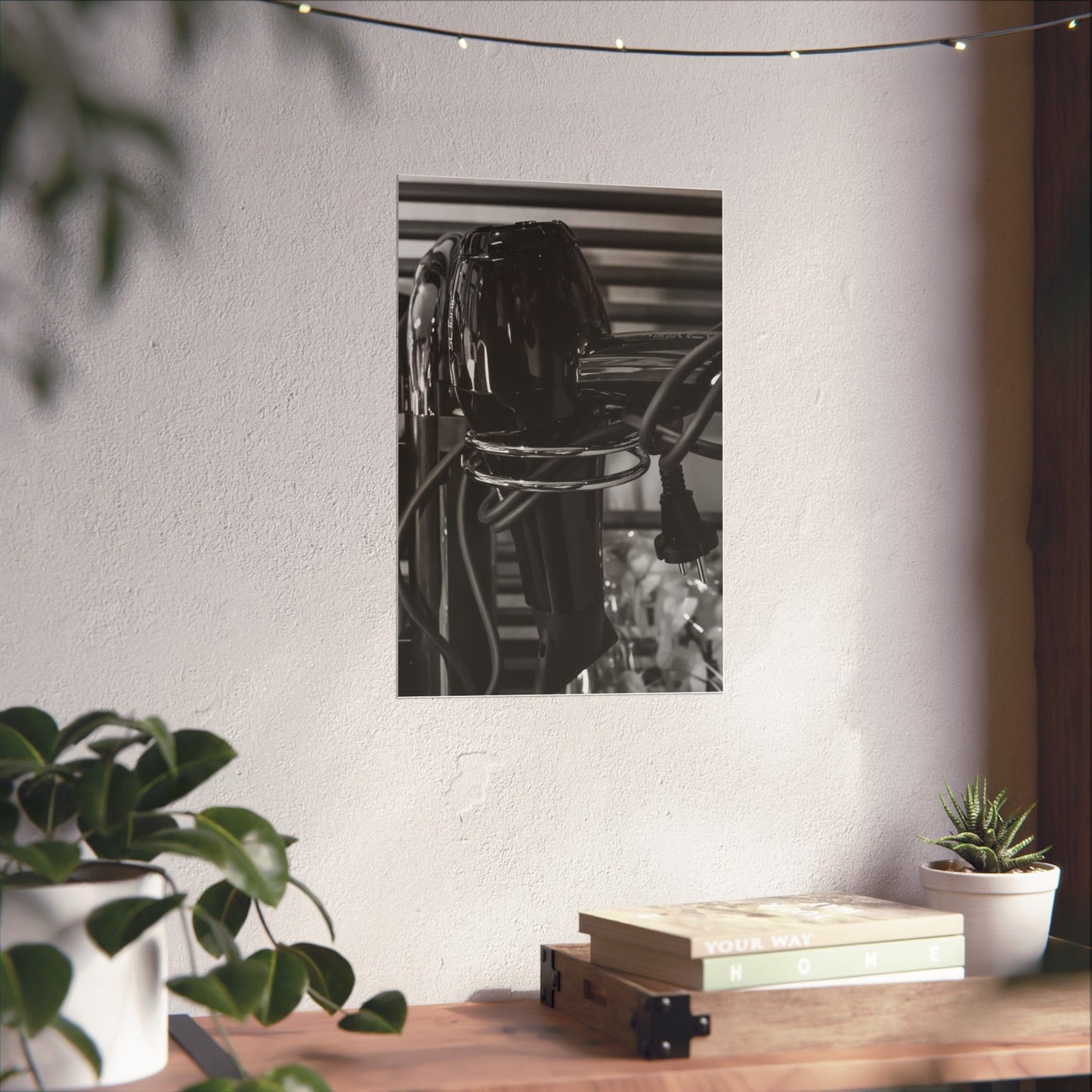 Decorative mirror on a wall with plants and books on a table below.