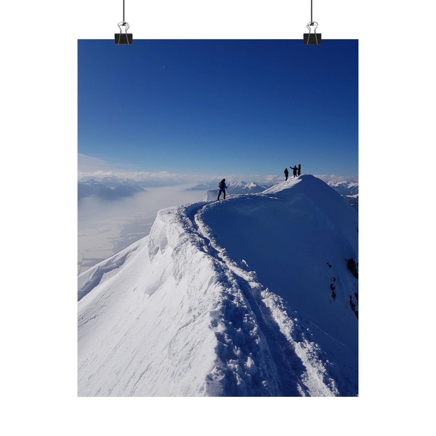 People standing on a snowy mountain peak with a clear blue sky