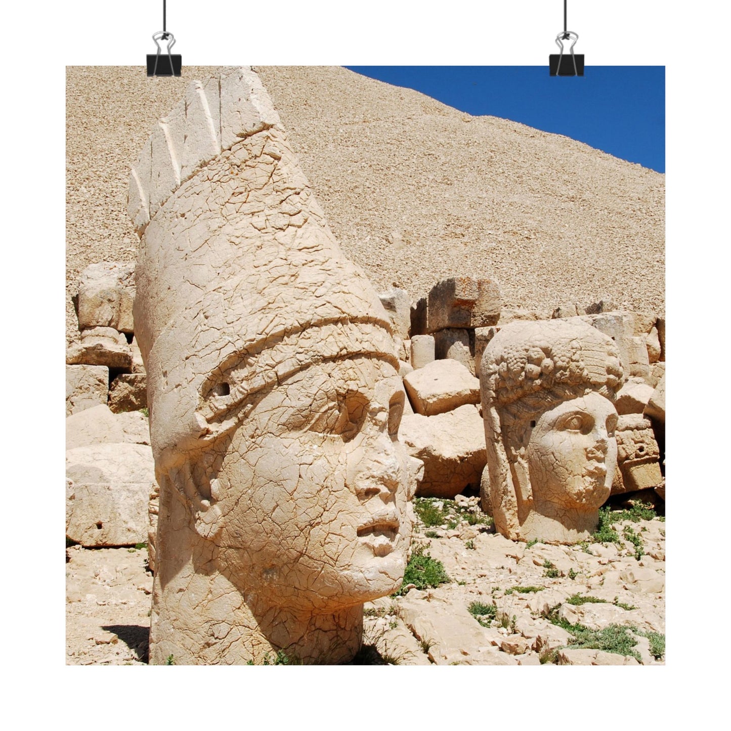 Stone heads of ancient statues on a rocky hillside with blue sky.