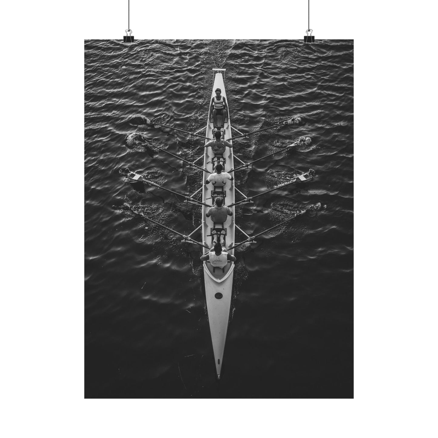Black and white photograph of a rowing boat with rowers on water