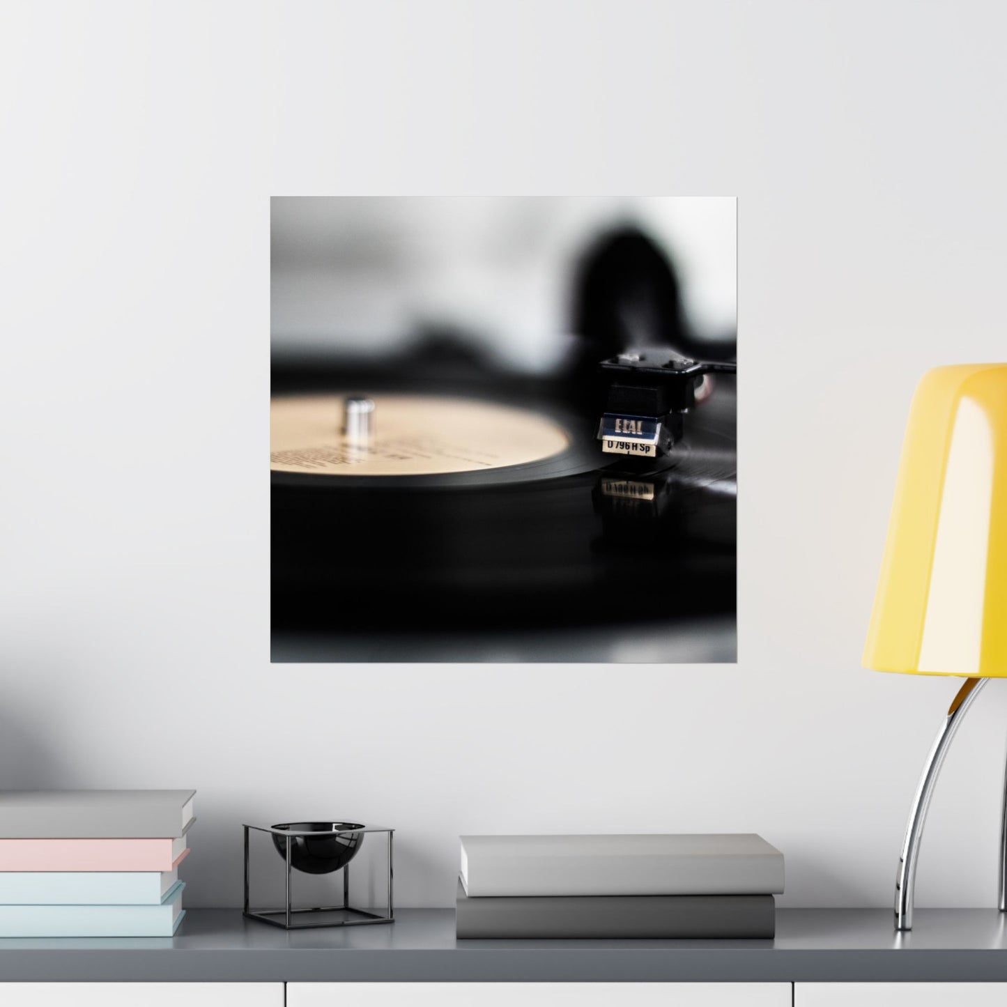 Turntable with vinyl record on a white surface with a yellow lamp in the background