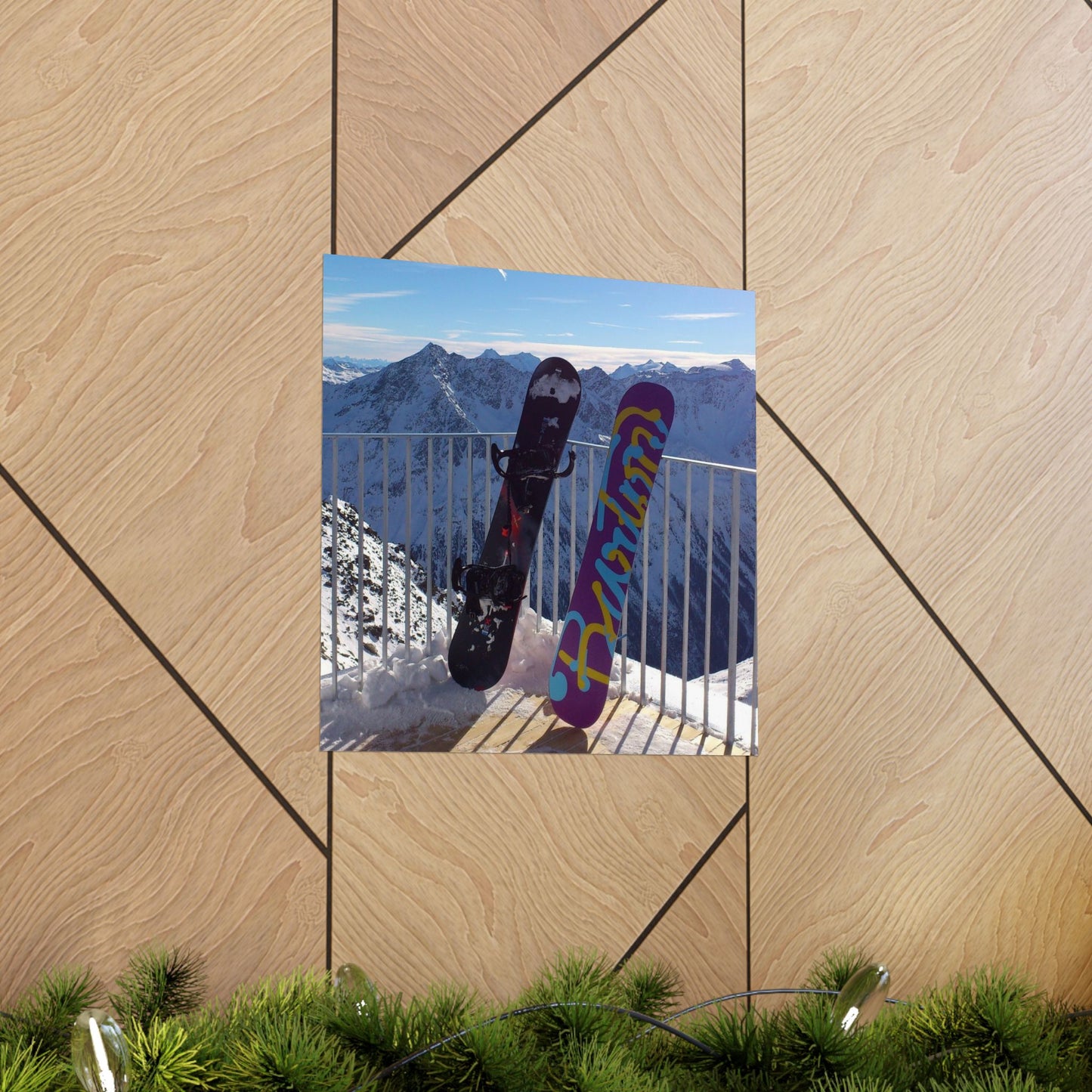 Two snowboards with colorful designs leaning against a railing with a mountain view.