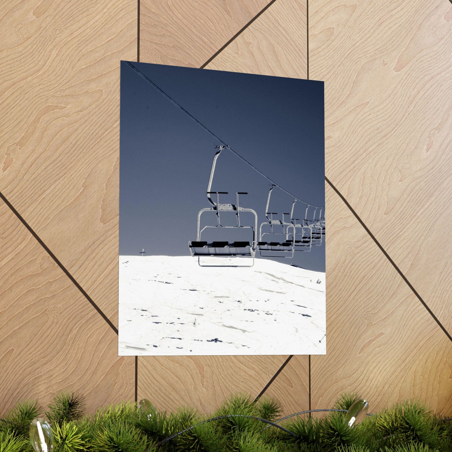 Ski lift against a blue sky on a snowy mountain, displayed on a wooden surface.