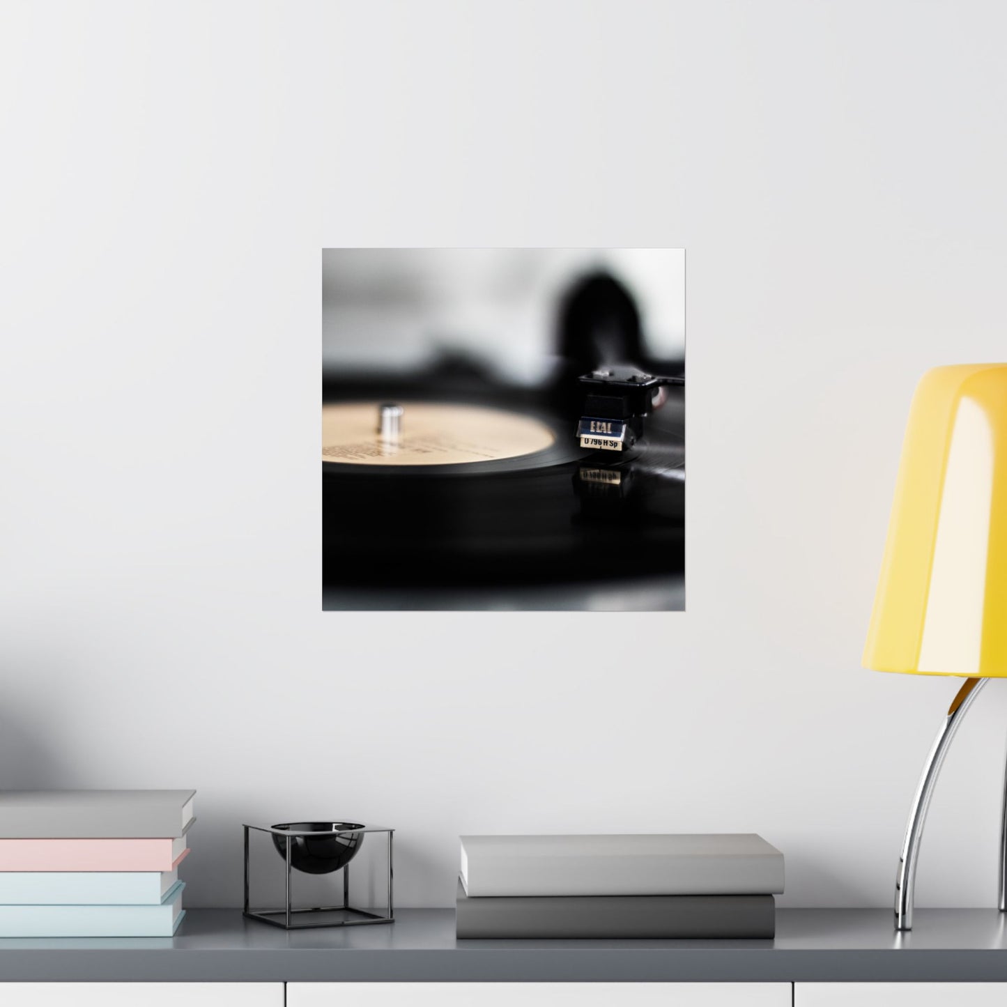 Turntable on a white wall with a yellow lamp and books on a shelf below.