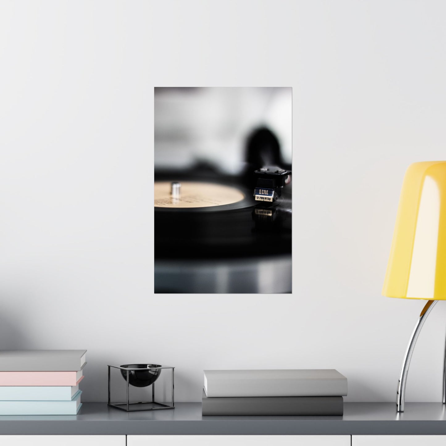 Framed artwork of a record player on a shelf with books and a lamp.