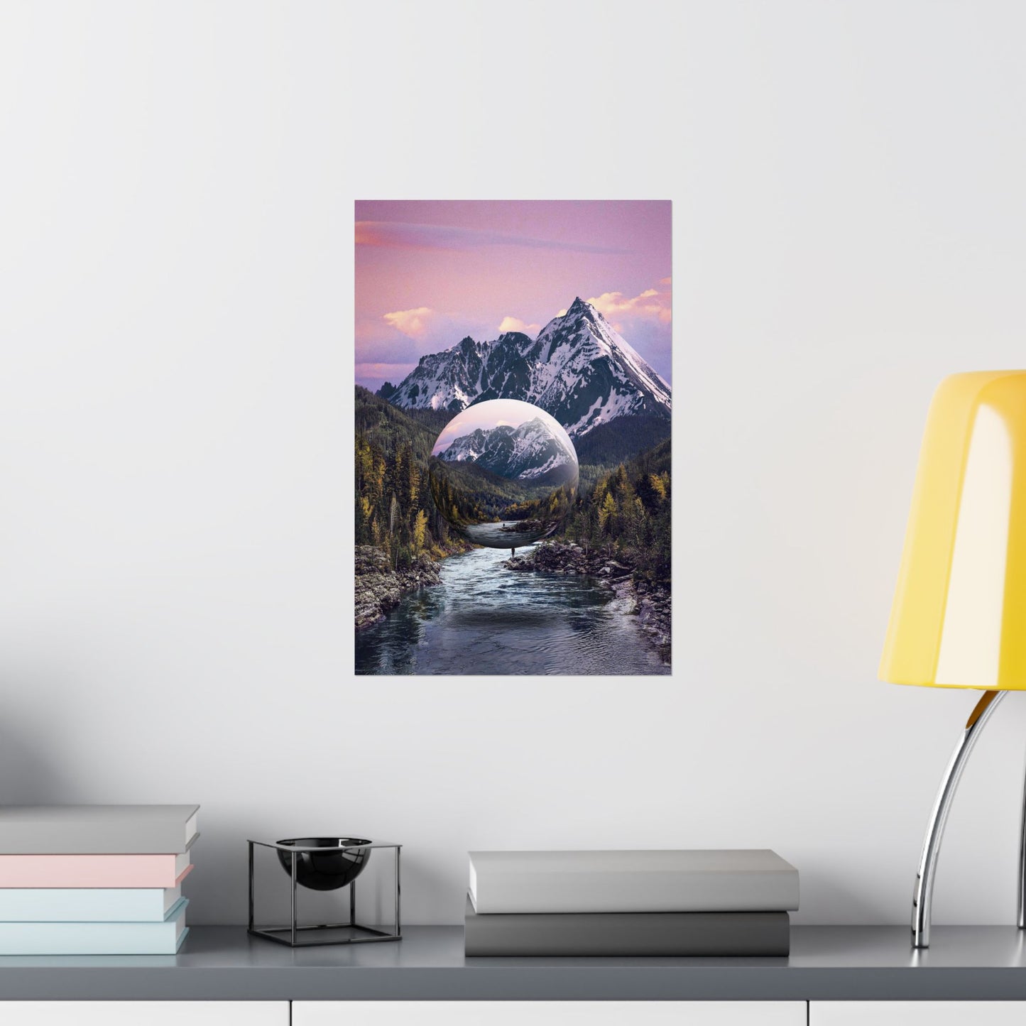 Framed artwork of a mountain landscape with a river and a purple sky on a white wall.