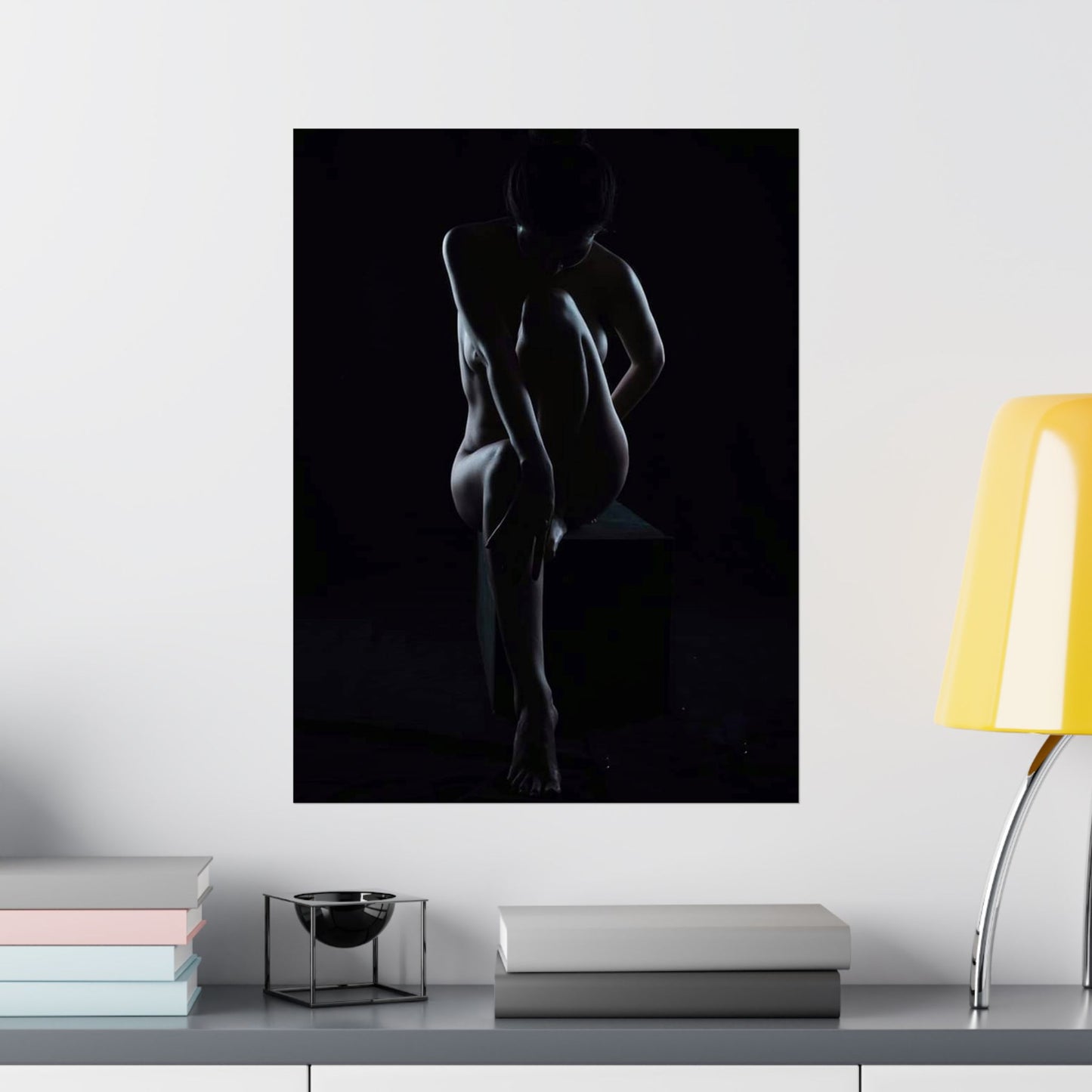 Silhouette of a nude figure on a black background in a modern interior setting.