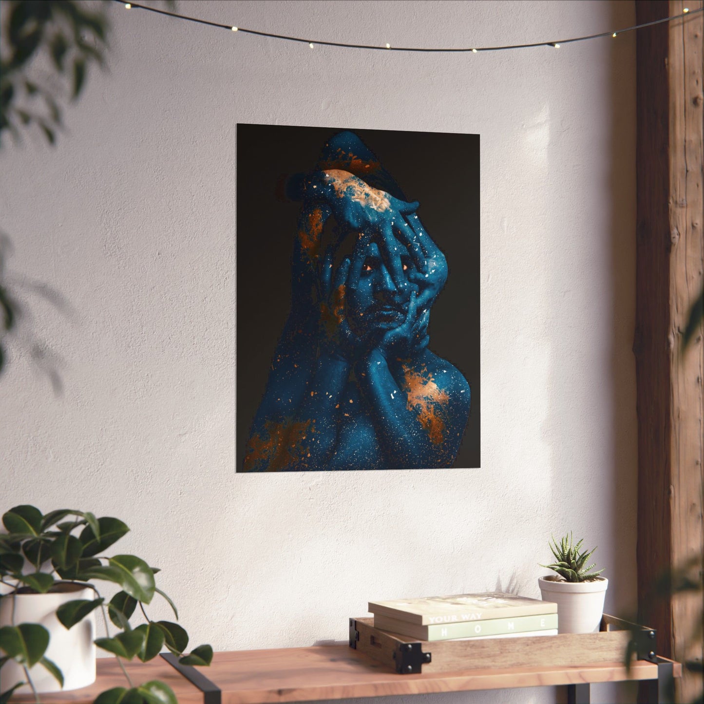 Artistic depiction of a blue figure with a dark background on a wall above a wooden table with plants.