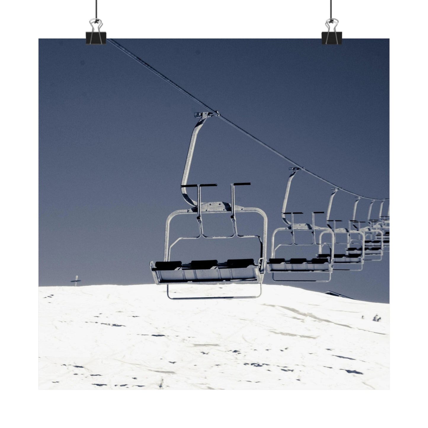 Ski lift chairs on a snowy mountain with a clear blue sky