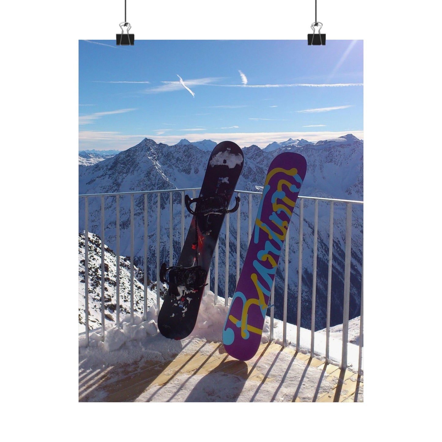 Two snowboards hanging on a railing with a mountainous landscape in the background