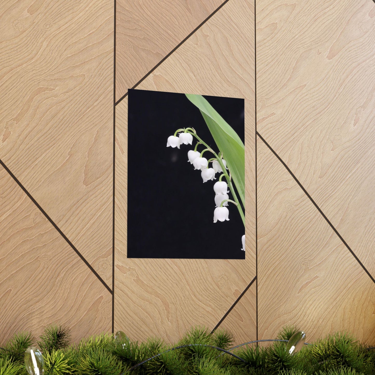 Framed picture of white flowers on a black background, leaning against a wooden wall.