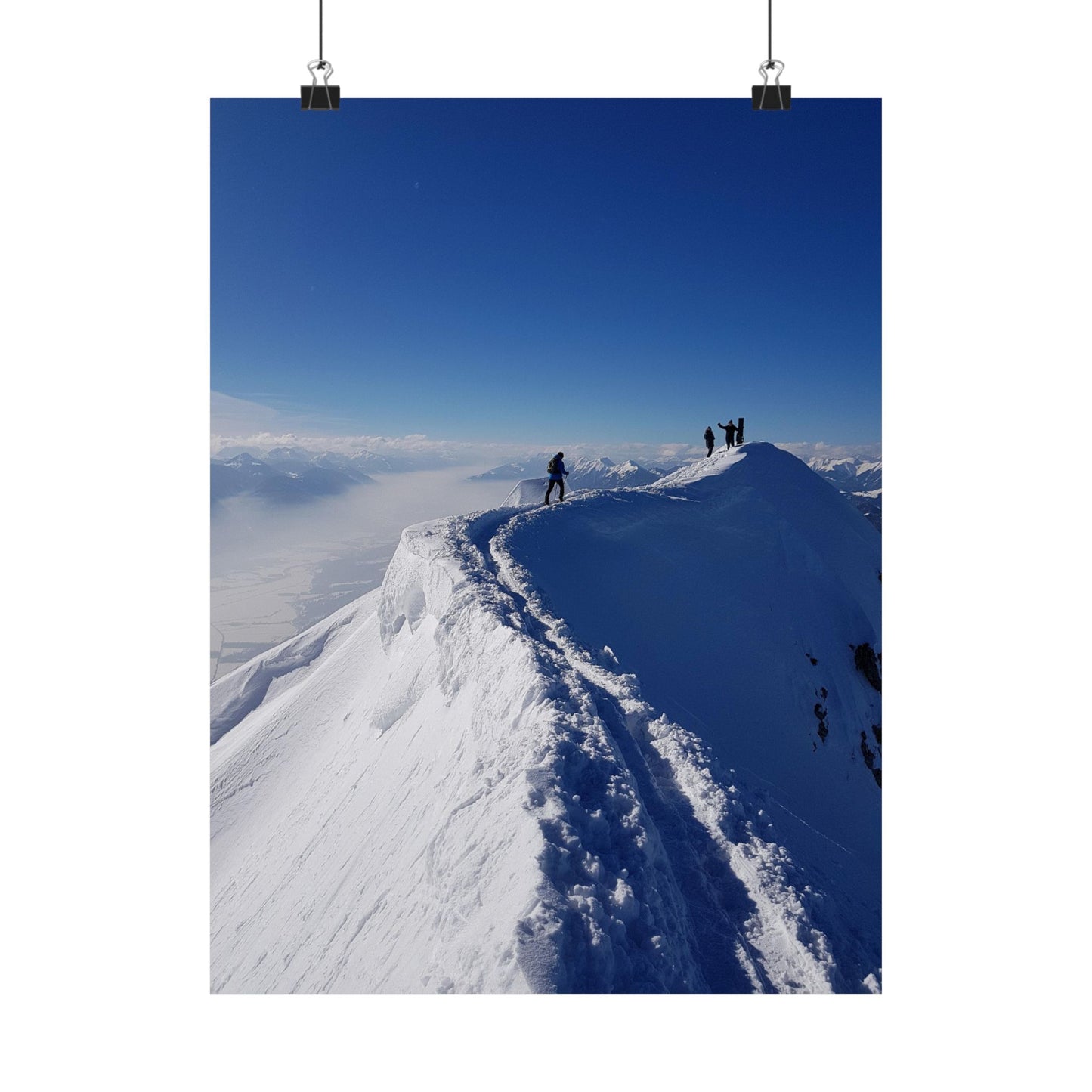 People hiking on a snow-covered mountain with a clear blue sky
