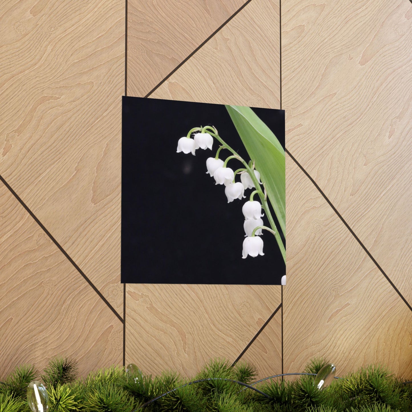 Decorative sign with white flowers on a black background, placed on a wooden surface.