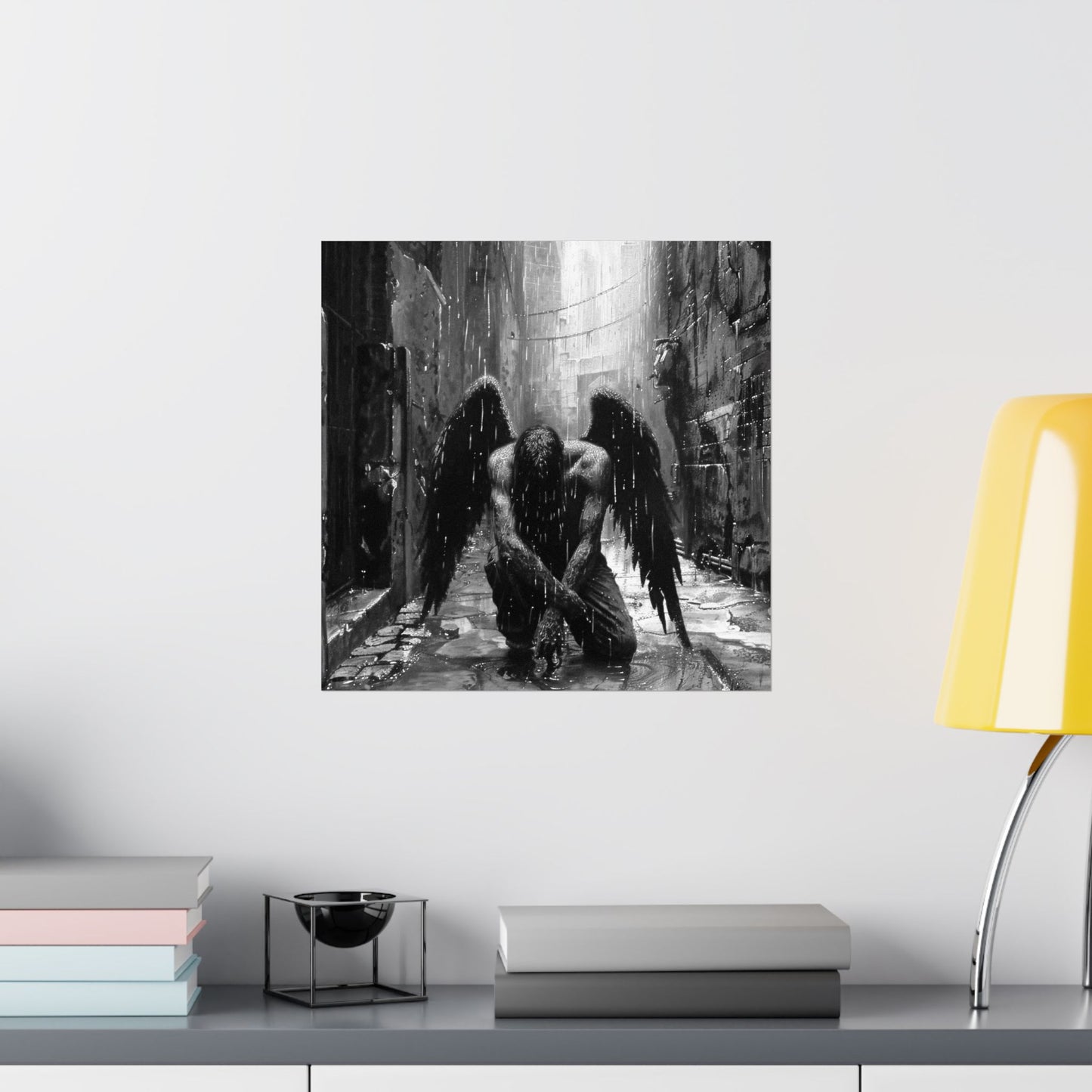 Framed artwork of a dark angel in a narrow alleyway on a wall above a shelf with books and a lamp.